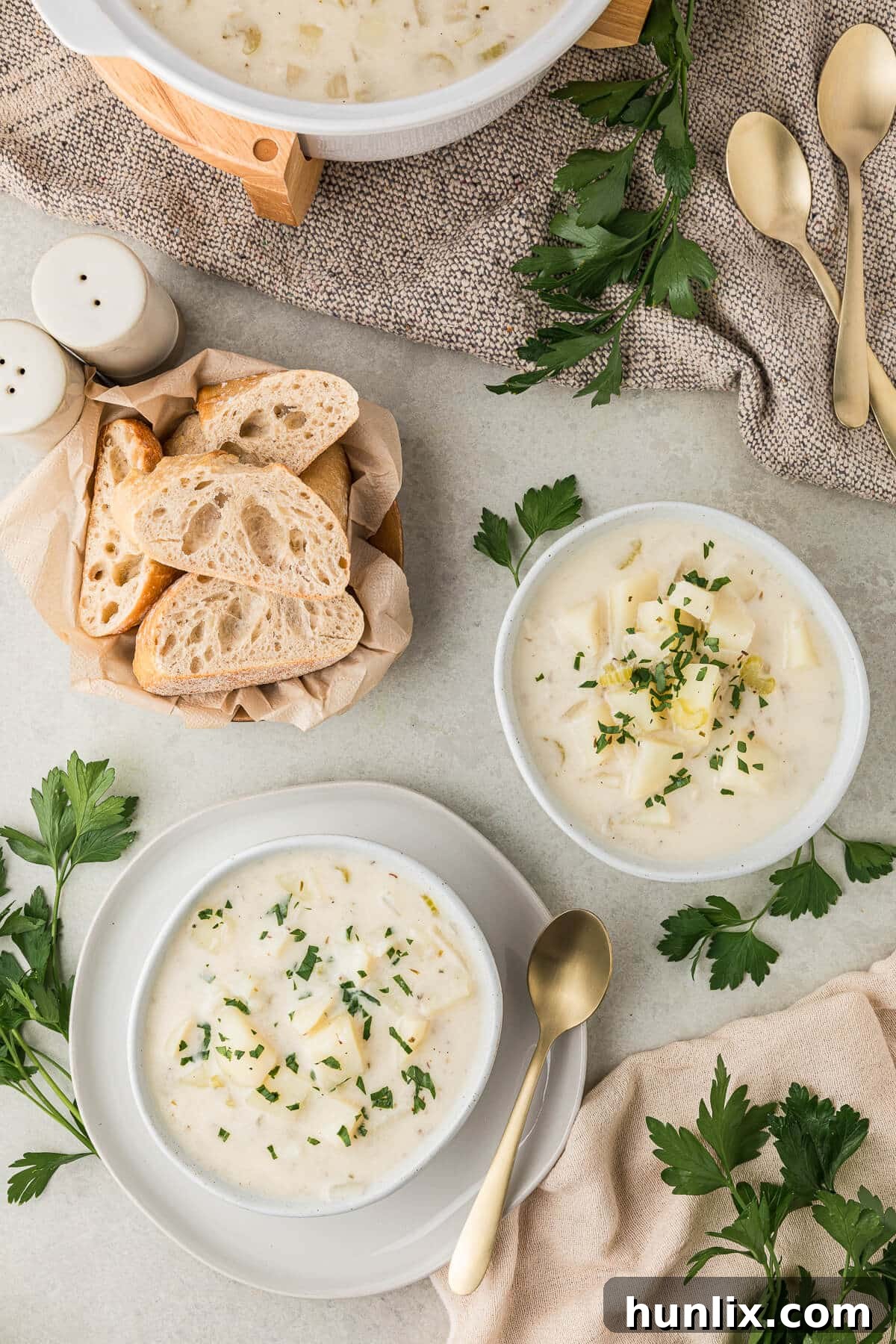 Two bowls of creamy German potato soup served with slices of fresh bread, highlighting a cozy meal.