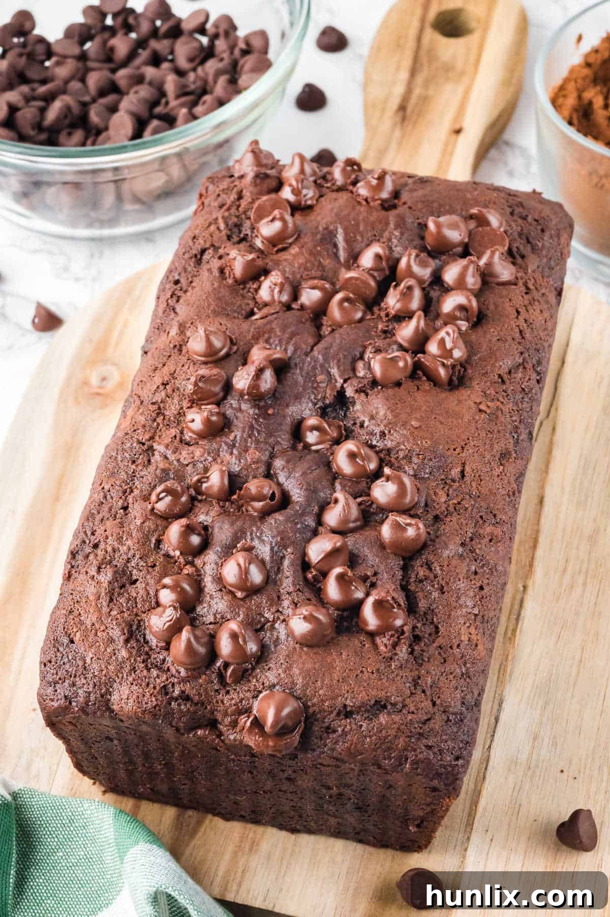 A chocolate zucchini bread loaf on a wooden cutting board, perfectly moist and rich.