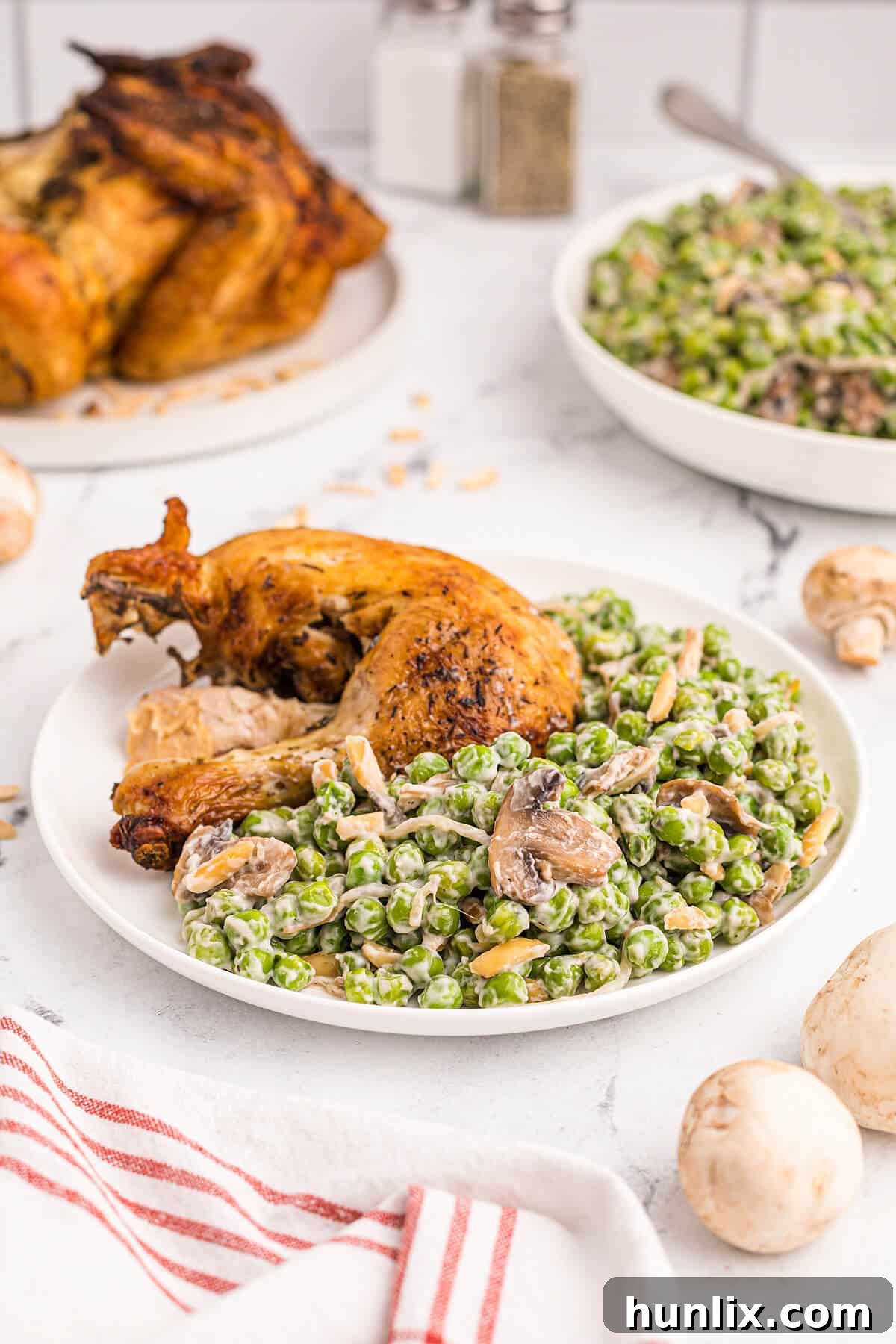 A plate featuring a generous serving of Company Peas alongside a piece of roasted chicken, illustrating a perfect meal pairing.