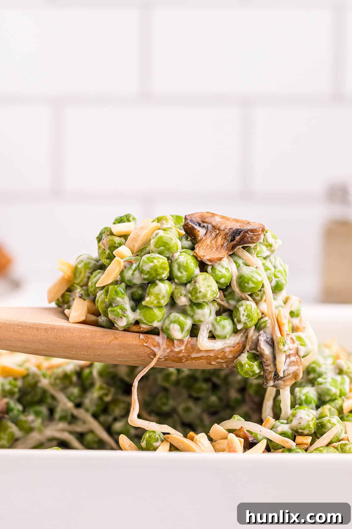 A close-up shot of Company Peas on a serving spoon, highlighting the creamy texture and visible pieces of mushroom and peas.