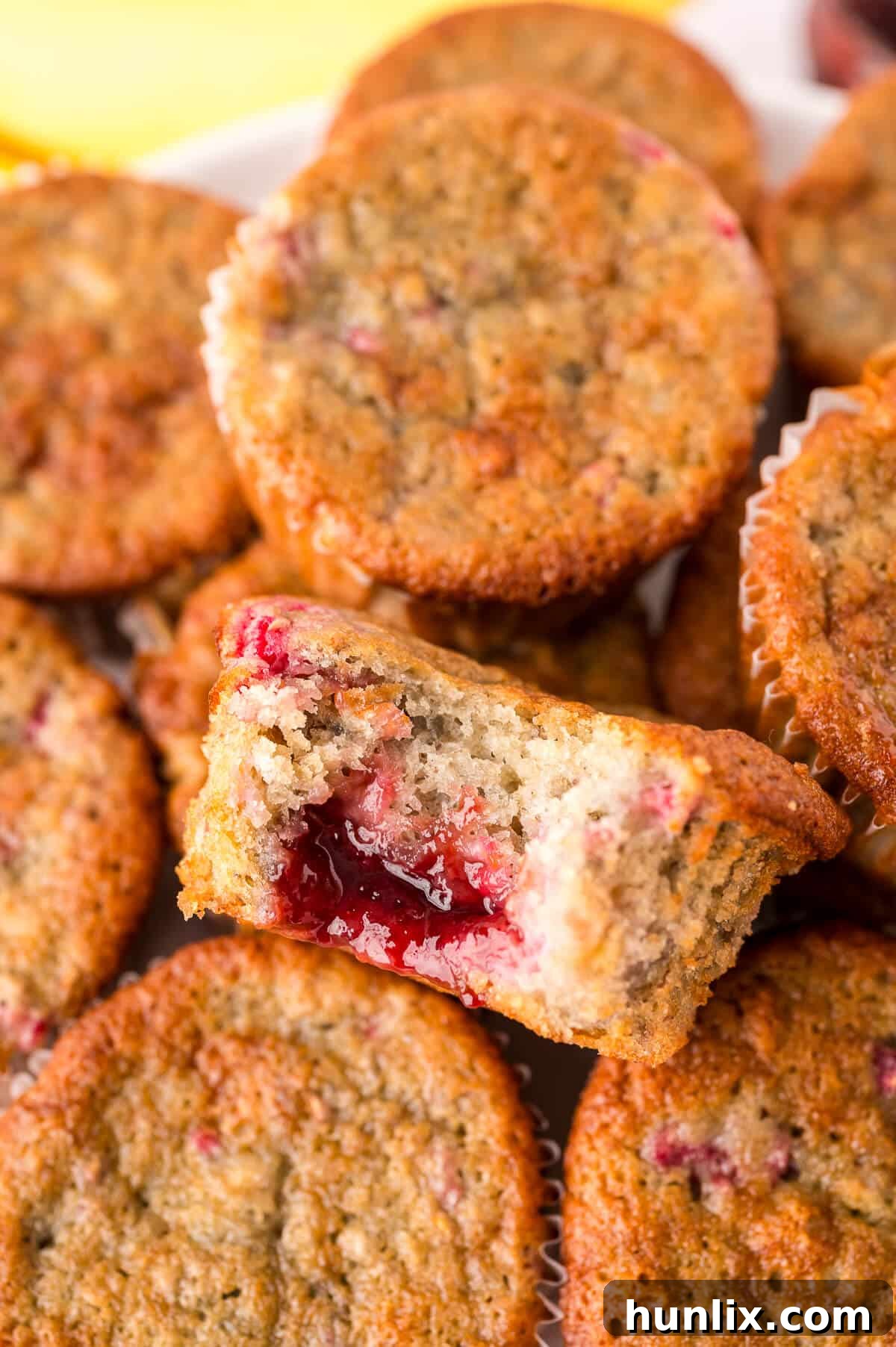 Golden Banana Raspberry Bliss Muffins 9 A generous pile of freshly baked Banana Raspberry Muffins arranged artistically, highlighting their inviting texture and rich color.