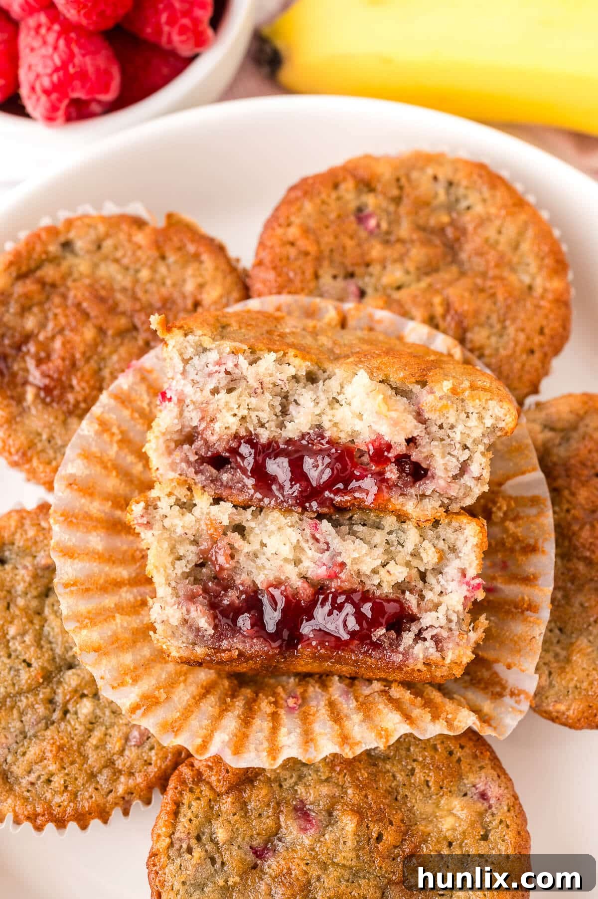 Golden Banana Raspberry Bliss Muffins 10 A freshly baked Banana Raspberry Muffin, cut in half to reveal its moist interior and the delicious raspberry jam center.
