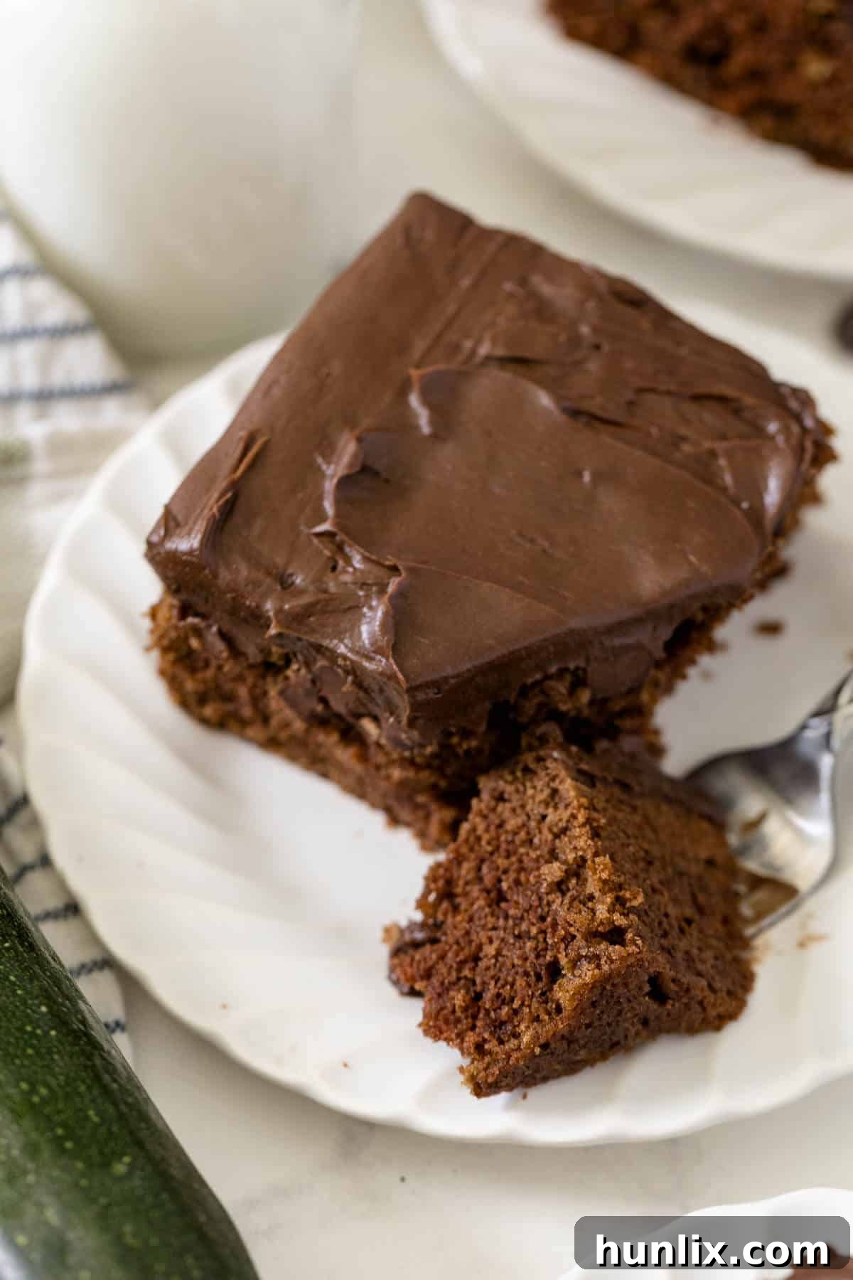 A close-up shot of a fork holding a delicious bite of chocolate zucchini cake, highlighting its rich, moist texture and the melted chocolate chips, enticing you to take a bite.