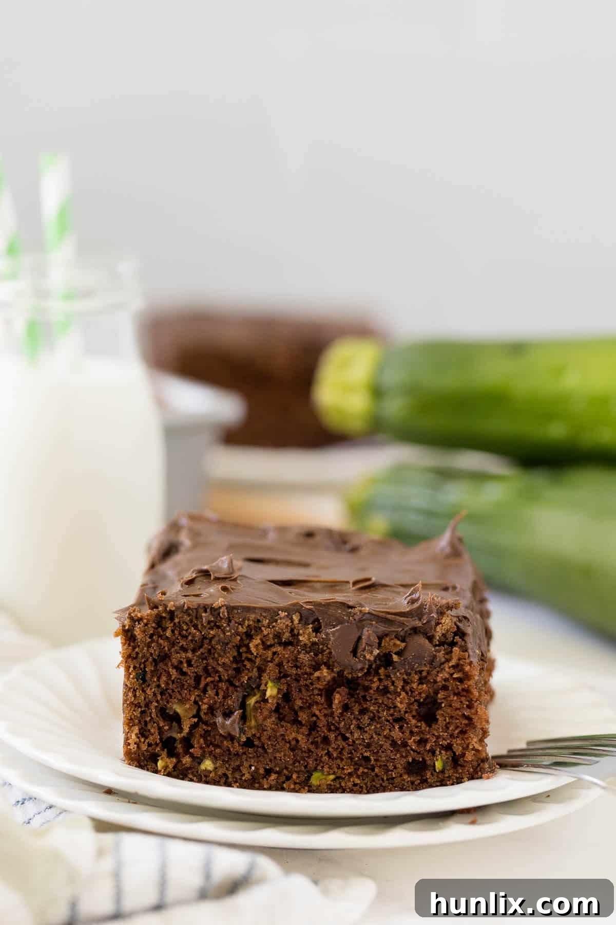 A perfectly portioned slice of moist chocolate zucchini cake resting elegantly on a pristine white plate, showcasing its rich texture and chocolate chip topping, ready to be enjoyed.