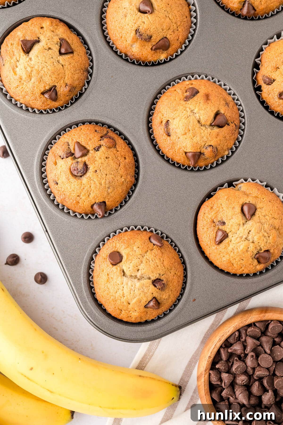 Decadent Banana Chocolate Chip Muffins 2 Freshly baked banana chocolate chip muffins arranged beautifully in a muffin pan, showcasing their golden-brown tops and melted chocolate chips.