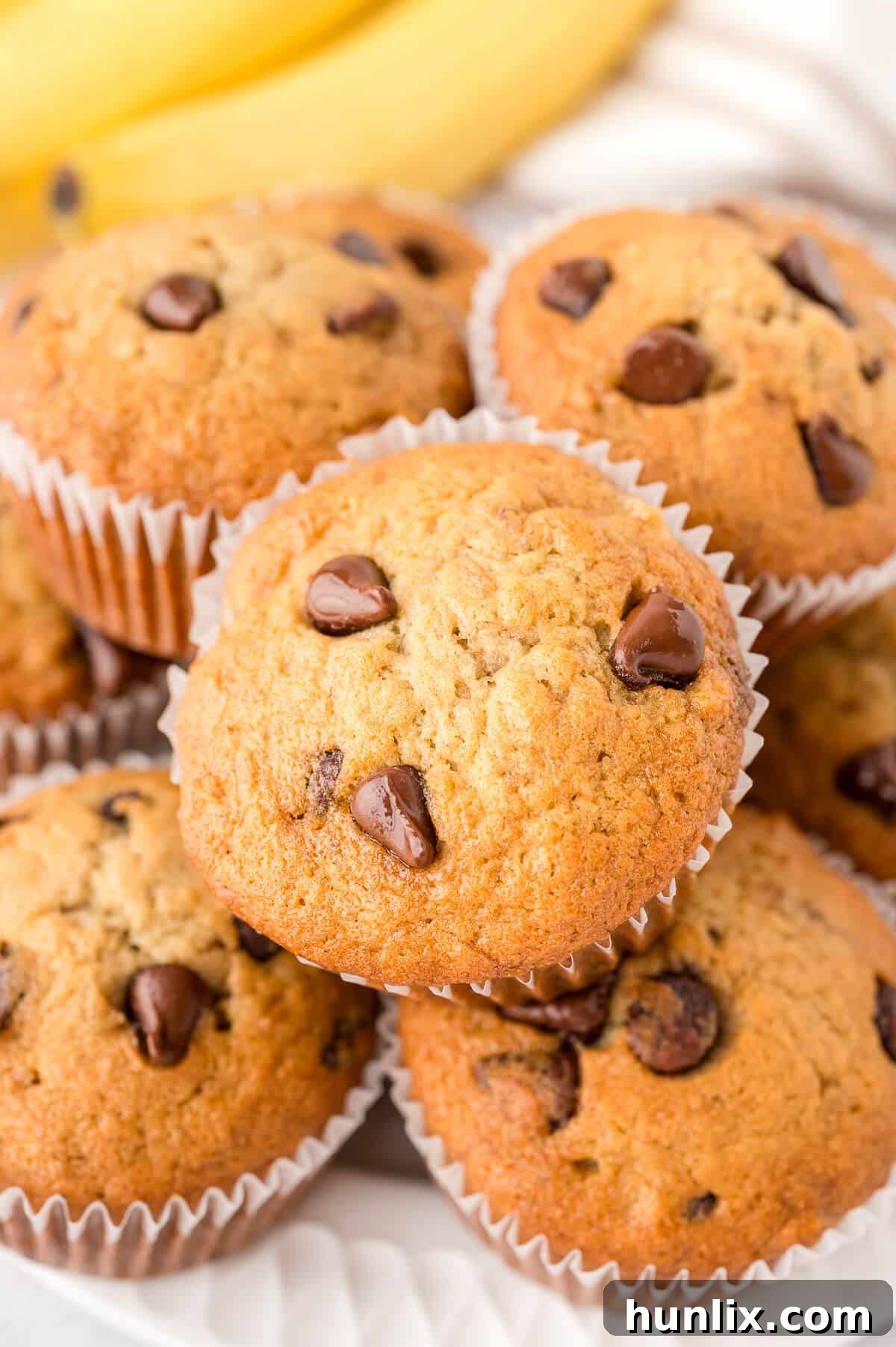 Decadent Banana Chocolate Chip Muffins 9 A delightful pile of golden-brown banana chocolate chip muffins, ready to be enjoyed.