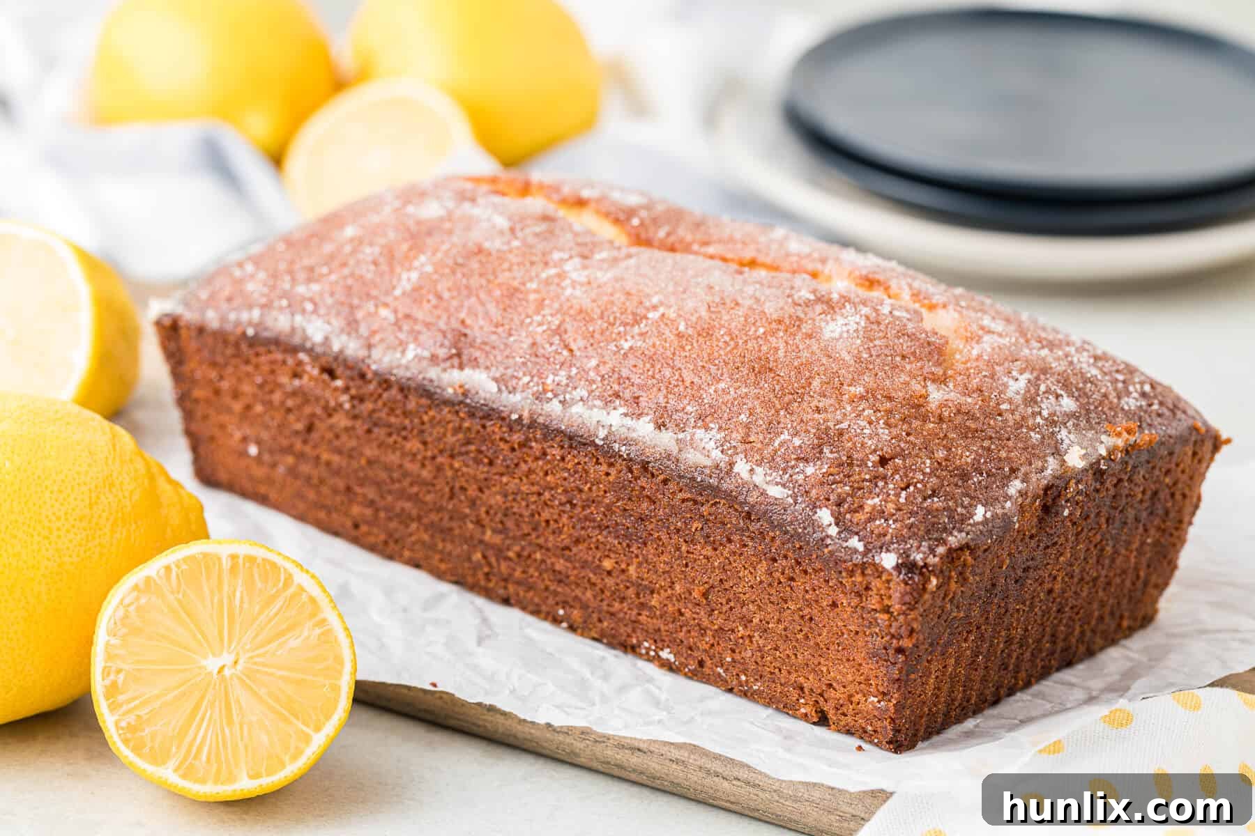 Golden lemon loaf cooling on parchment paper, ready for glazing.
