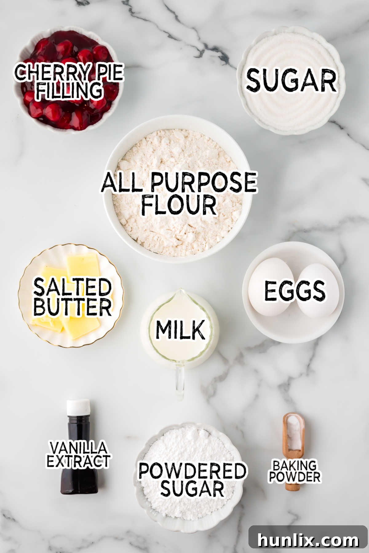 Assortment of ingredients for cherry cake on a marble counter, including butter, sugar, eggs, flour, baking powder, vanilla extract, and canned cherry pie filling.