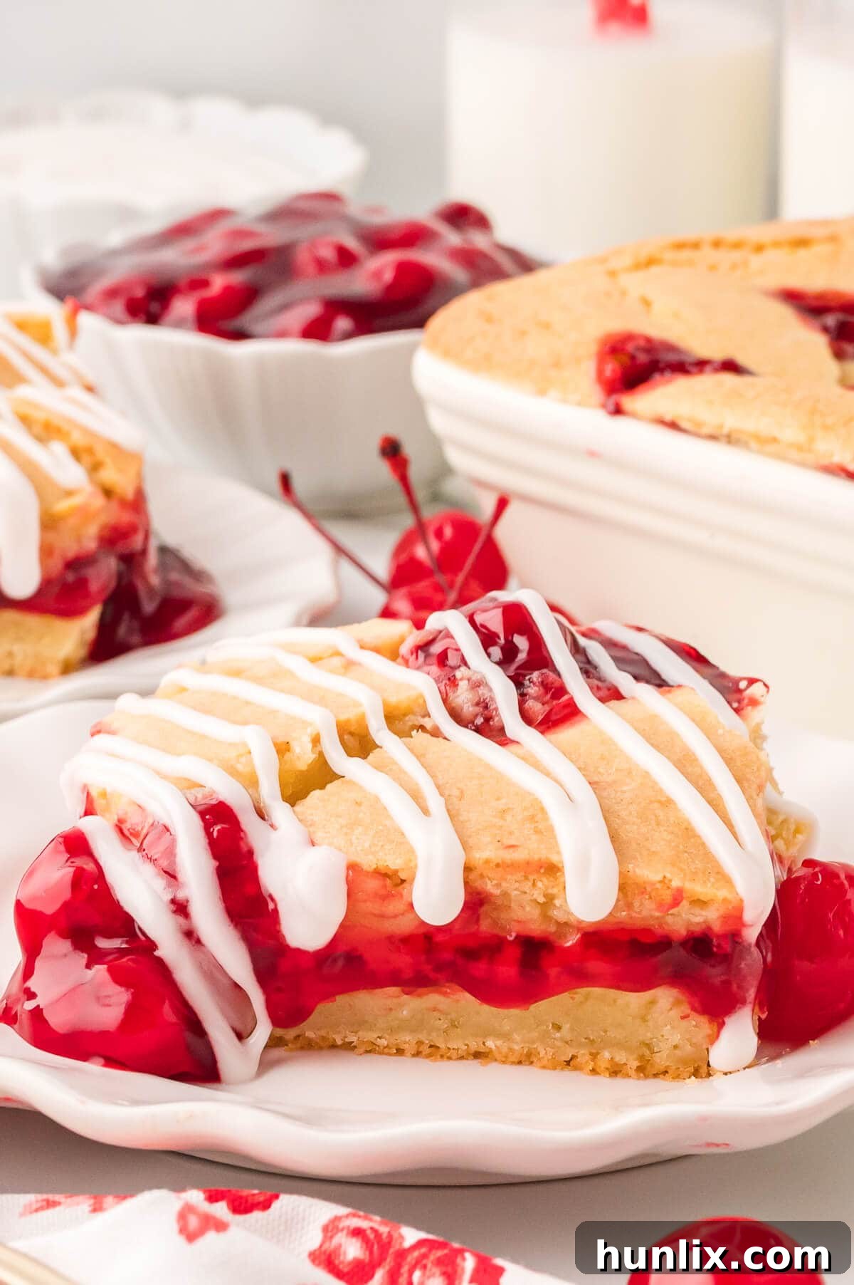 A beautifully glazed slice of cherry cake on a white plate, ready to be enjoyed.