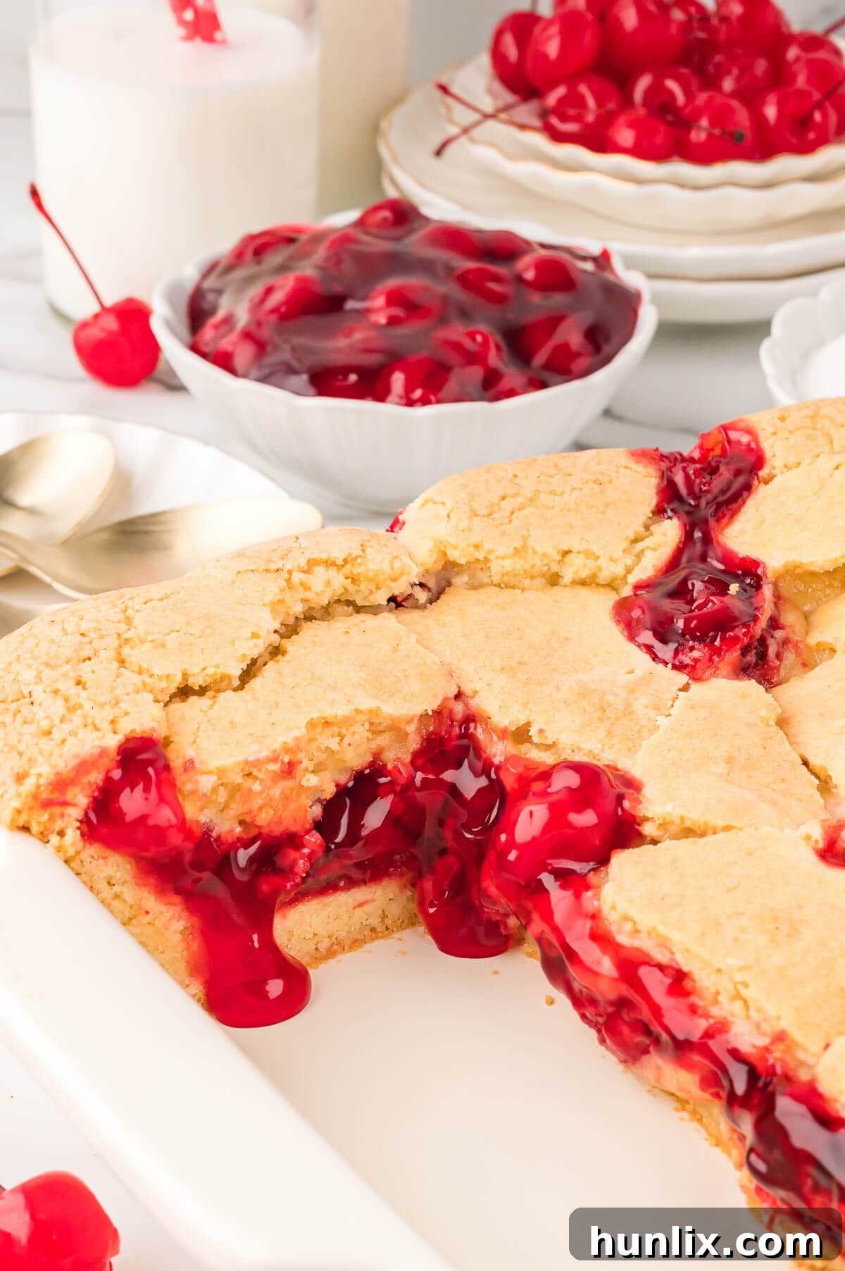 The baked cherry cake in a pan with several slices already cut out, ready for serving.