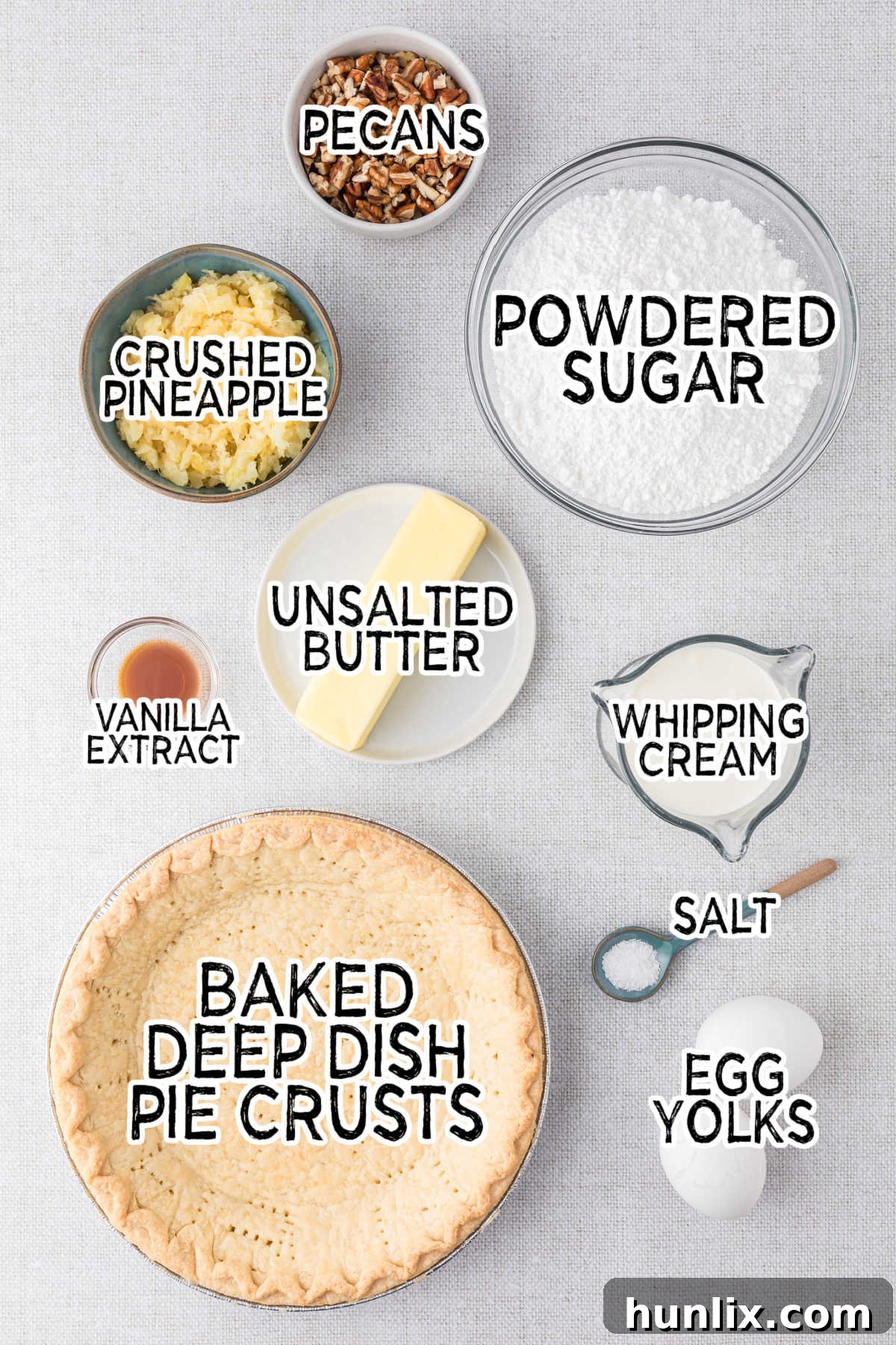 A colorful arrangement of fresh ingredients for Millionaire Pie, including a bowl of powdered sugar, egg yolks, vanilla, butter, pecans, salt, and a can of crushed pineapple, all ready to be transformed into a delicious dessert.