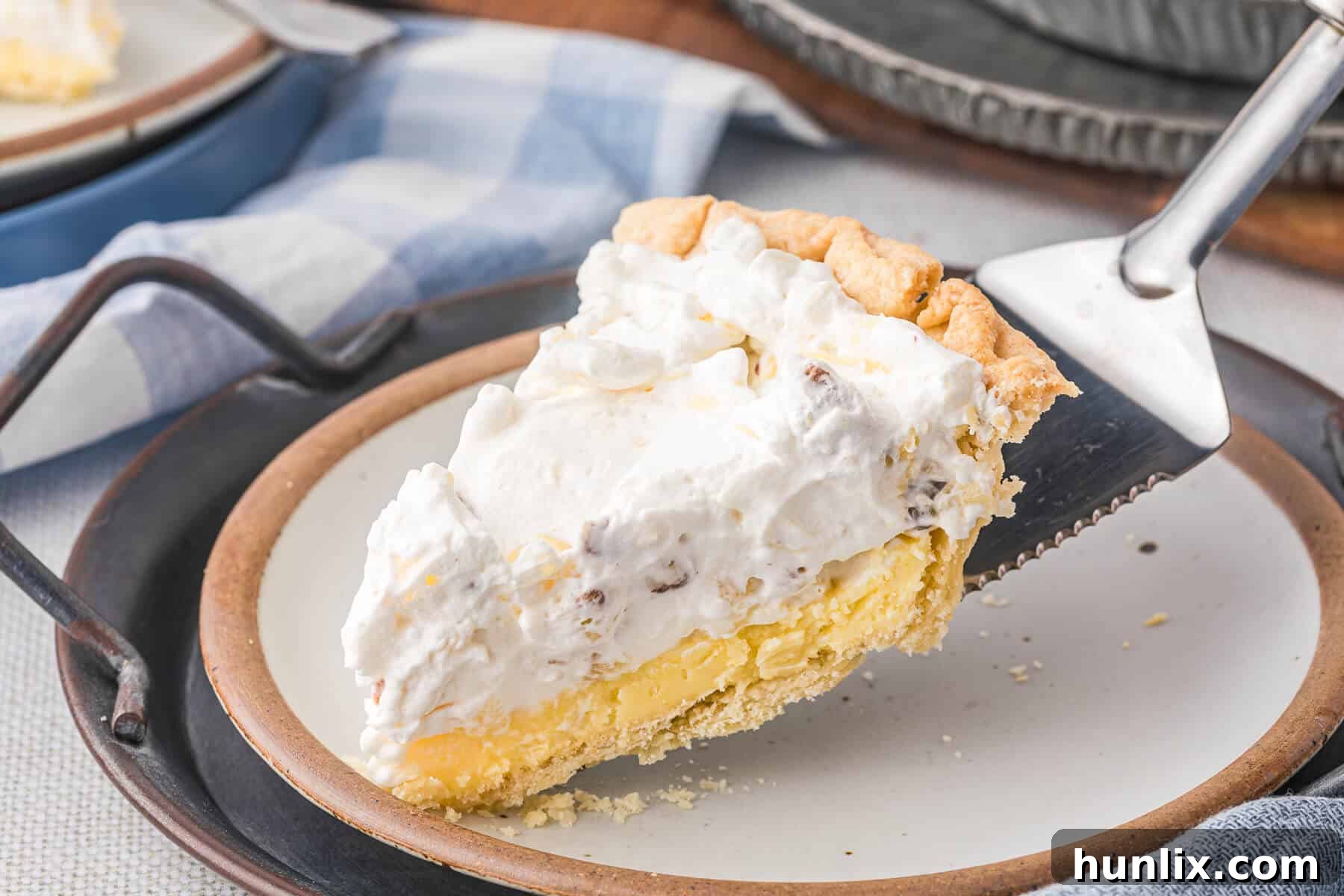 A delectable slice of Millionaire Pie sits on a pie serving spatula, highlighting its rich, multi-layered texture and inviting appearance.