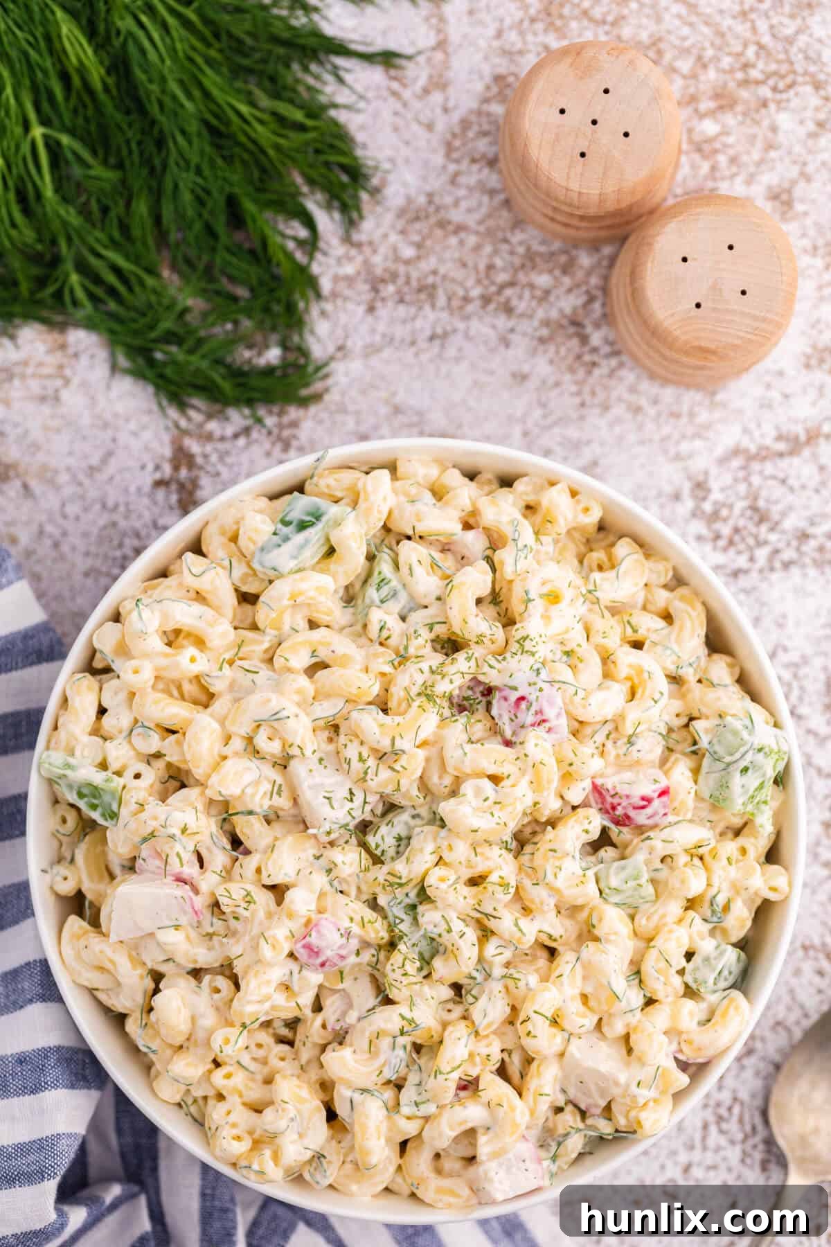 Macaroni Dill Salad in a white bowl, garnished with fresh dill.
