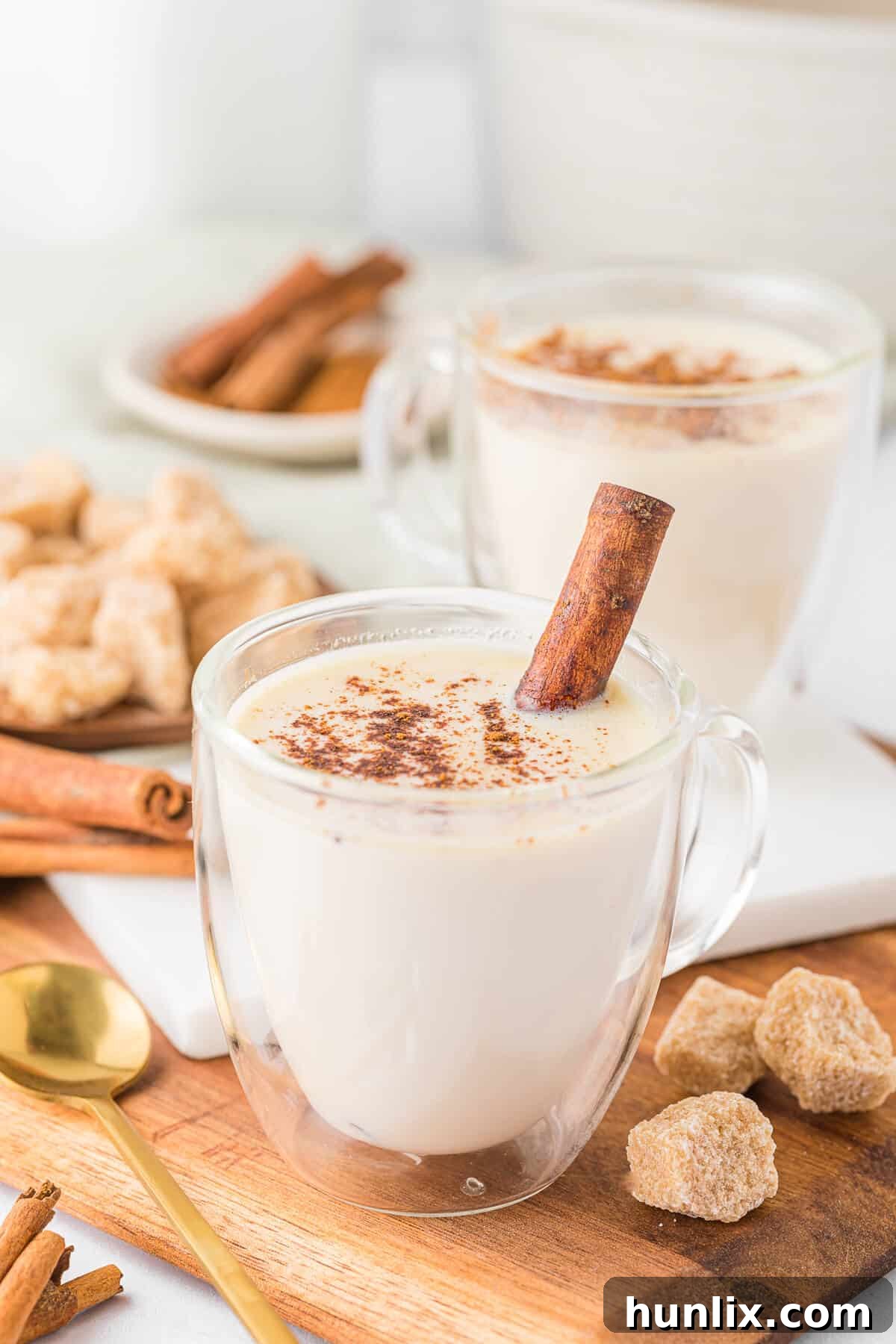 A warm, creamy butterscotch steamer in a glass mug, garnished with a cinnamon stick, inviting a sense of comfort and coziness.