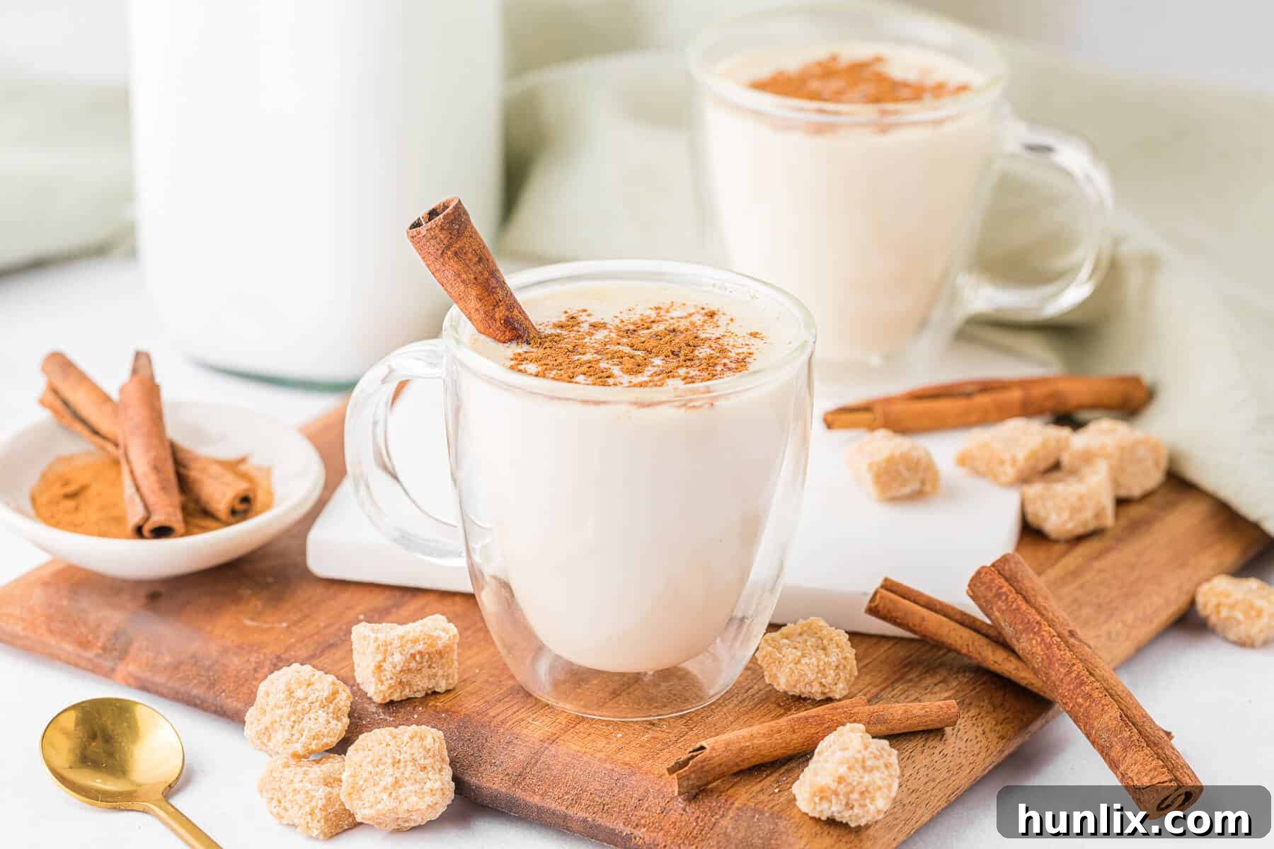A close-up shot of a butterscotch steamer in a glass mug, garnished with a single cinnamon stick, highlighting its inviting warmth and creamy texture.