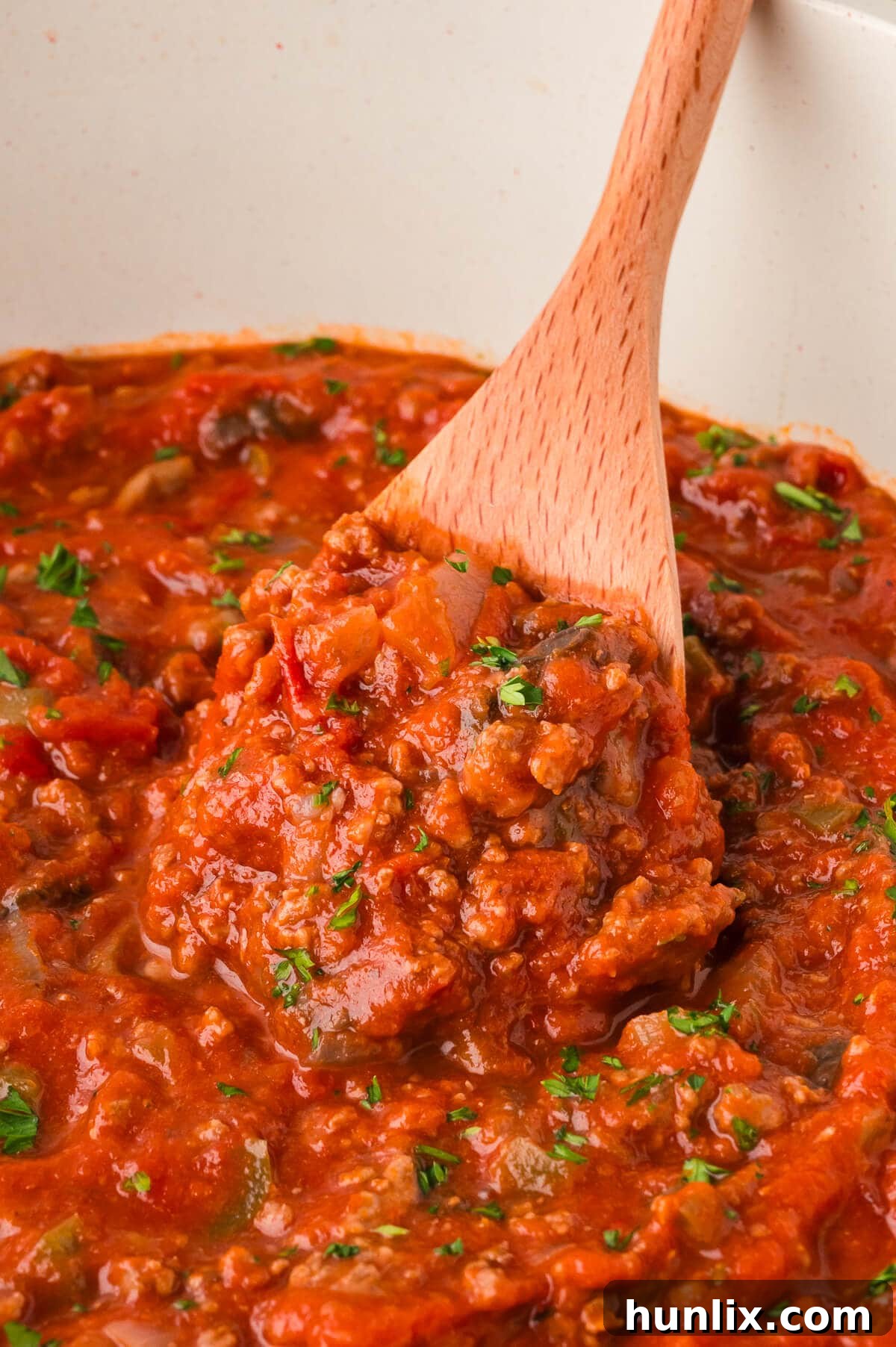 Mama's Perfect Pasta Sauce 6 A large pot of perfectly cooked homemade spaghetti sauce with a wooden spoon, ready to be served.