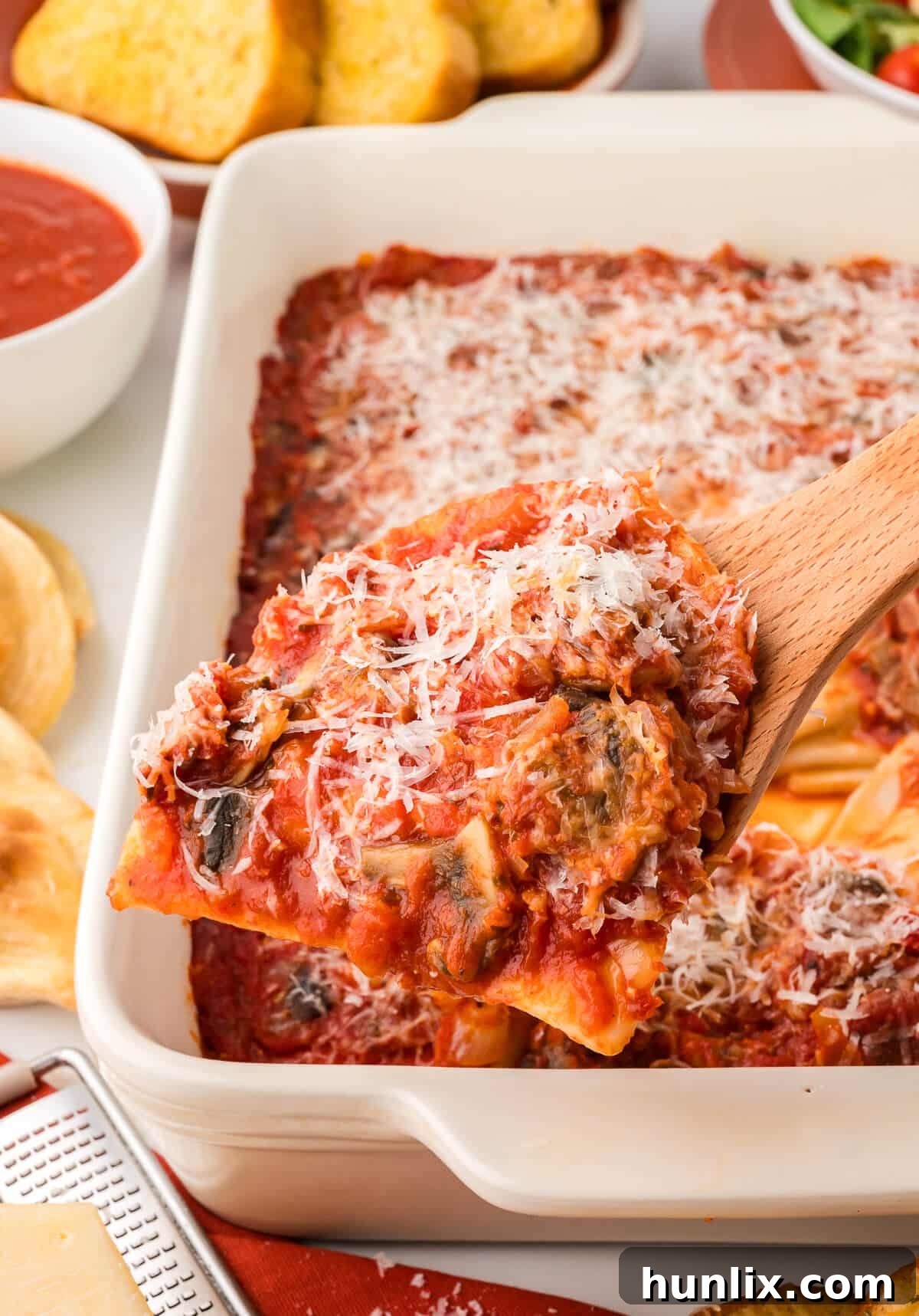 Hearty Homestyle Pierogi Casserole 7 A wooden spoon scooping out a portion of the Pierogi casserole, showcasing the layers of pierogies, sauce, and melted cheese.