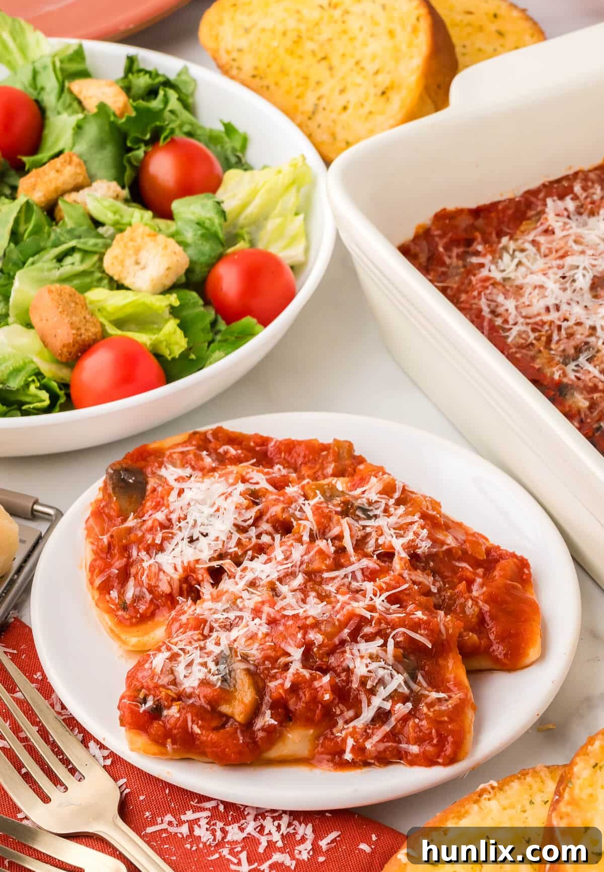 Hearty Homestyle Pierogi Casserole 8 A serving of Pierogi casserole on a white plate, showcasing the rich sauce and melted Parmesan cheese.