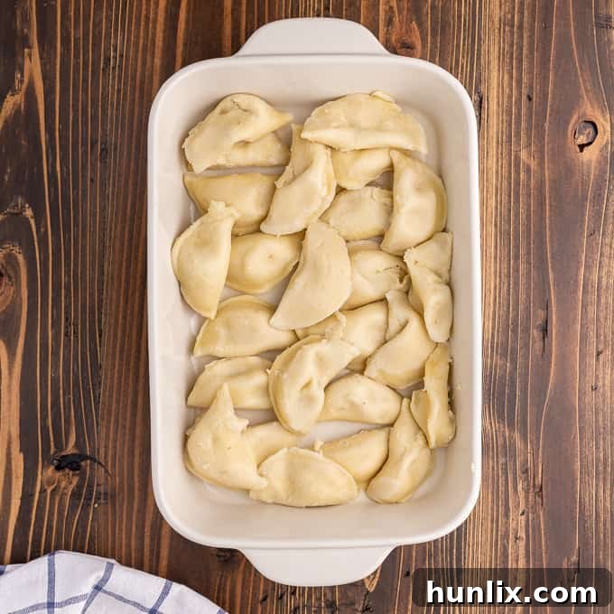 Creamy Chicken Pierogi Bake 4 Cooked pierogies neatly arranged in a 9x13 inch casserole dish, ready for toppings.