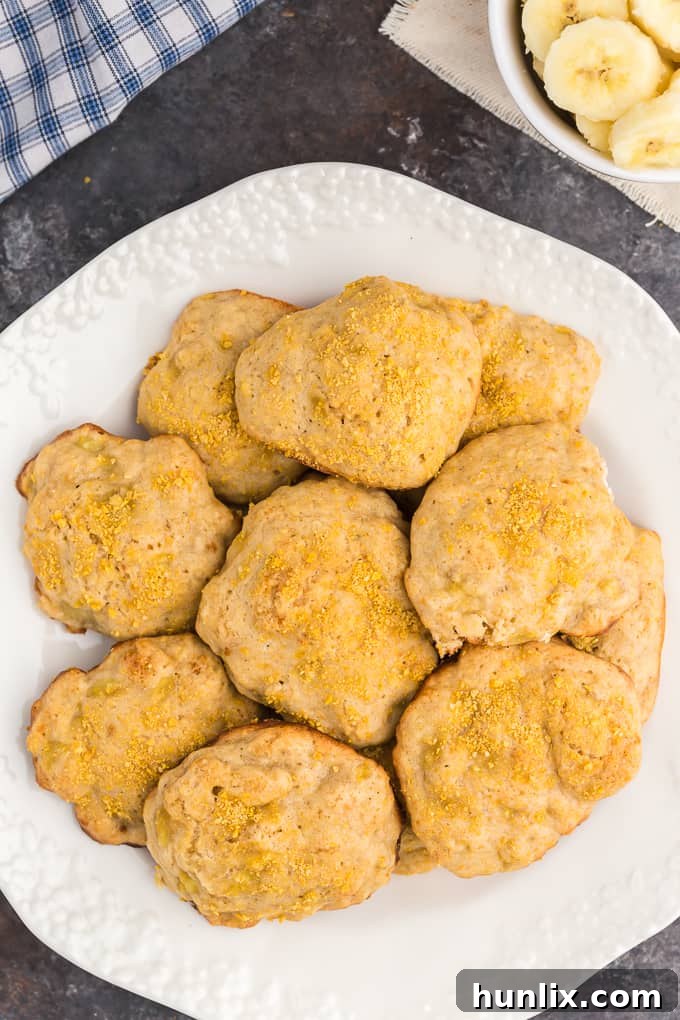 A single, perfectly baked banana cookie, warm and inviting, resting on a white surface.