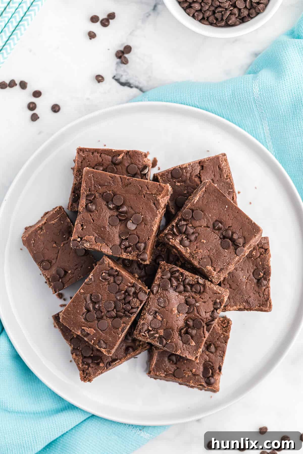 Individual squares of chocolate cake batter fudge presented neatly on a white plate.