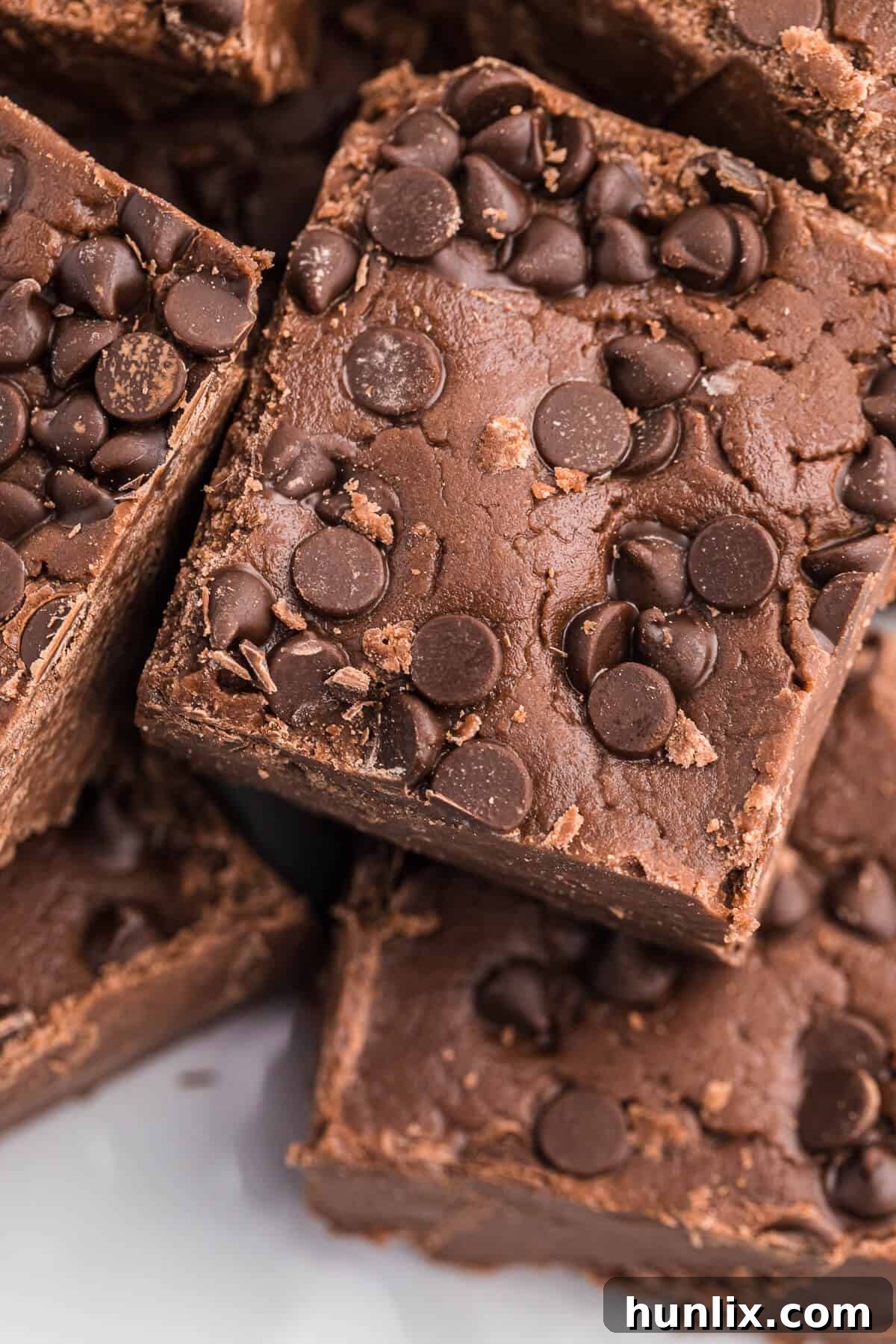 A close-up shot of a single square of chocolate cake batter fudge, highlighting its dense, rich texture and chocolate chips.