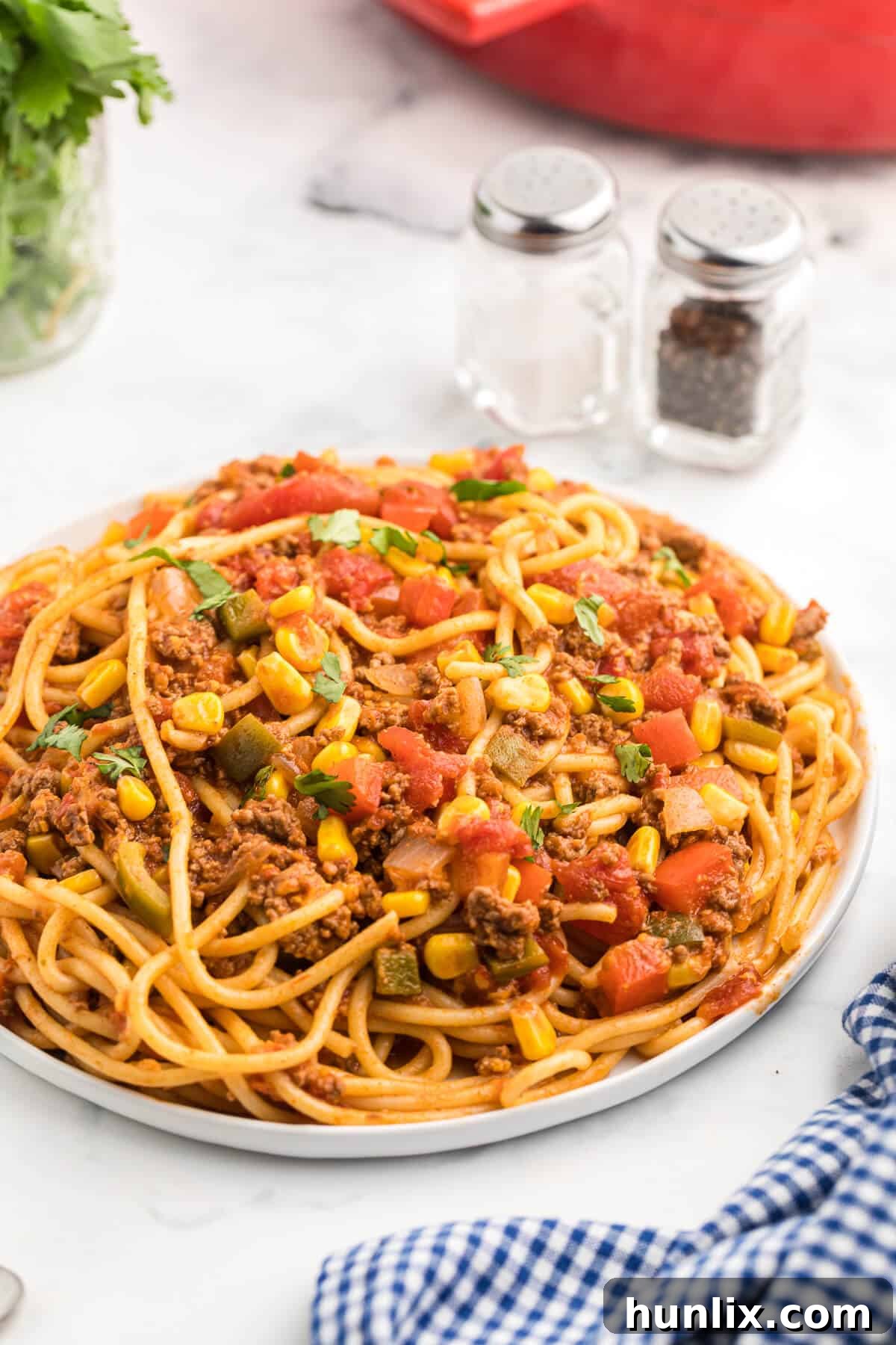A serving of Mexican spaghetti artfully placed on a white plate, set on a bright white surface, highlighting its vibrant colors.
