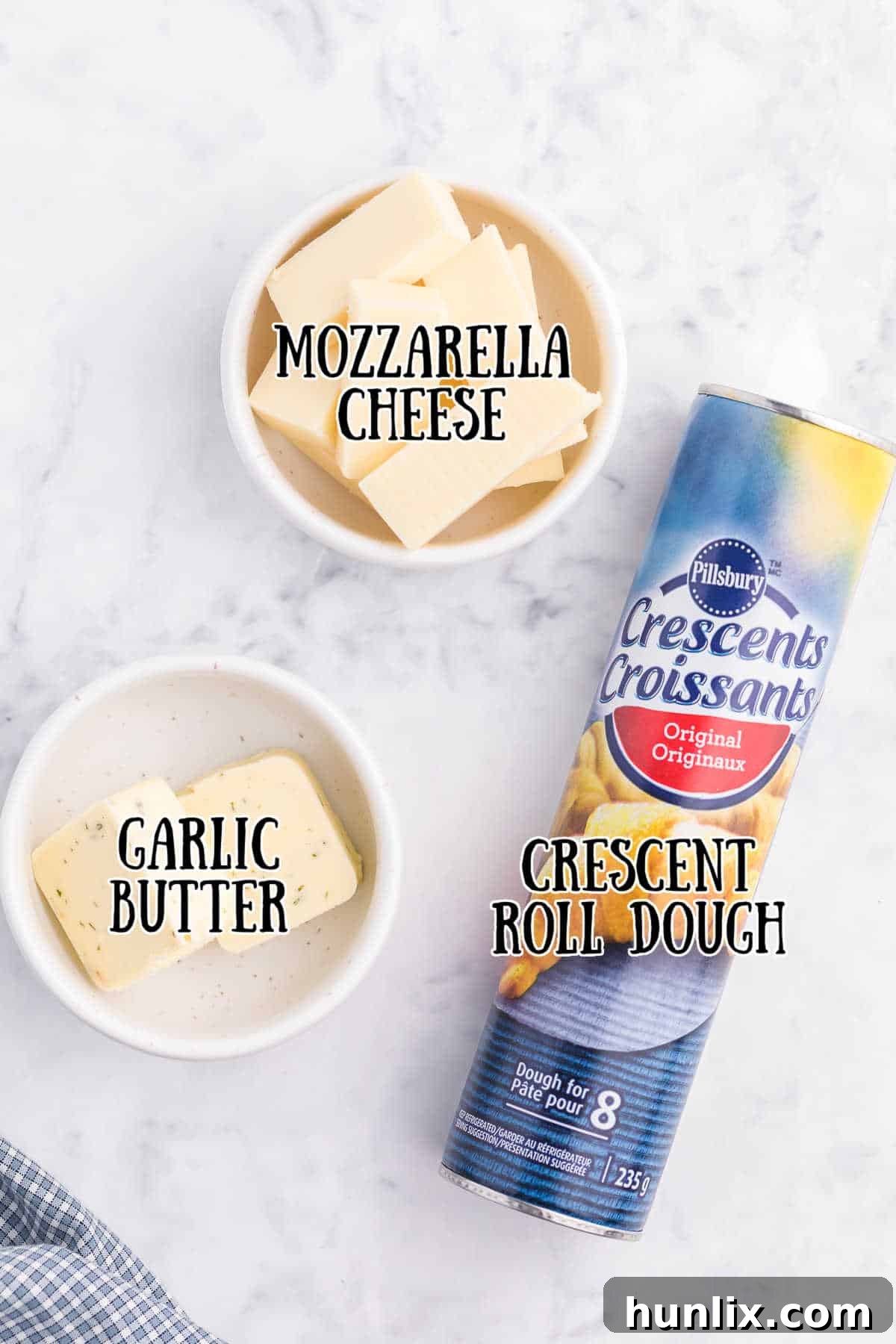 Ingredients for Air Fryer Garlic Cheese Stuffed Crescent Rolls on a white marble counter, including crescent roll dough, mozzarella cheese, and garlic butter.