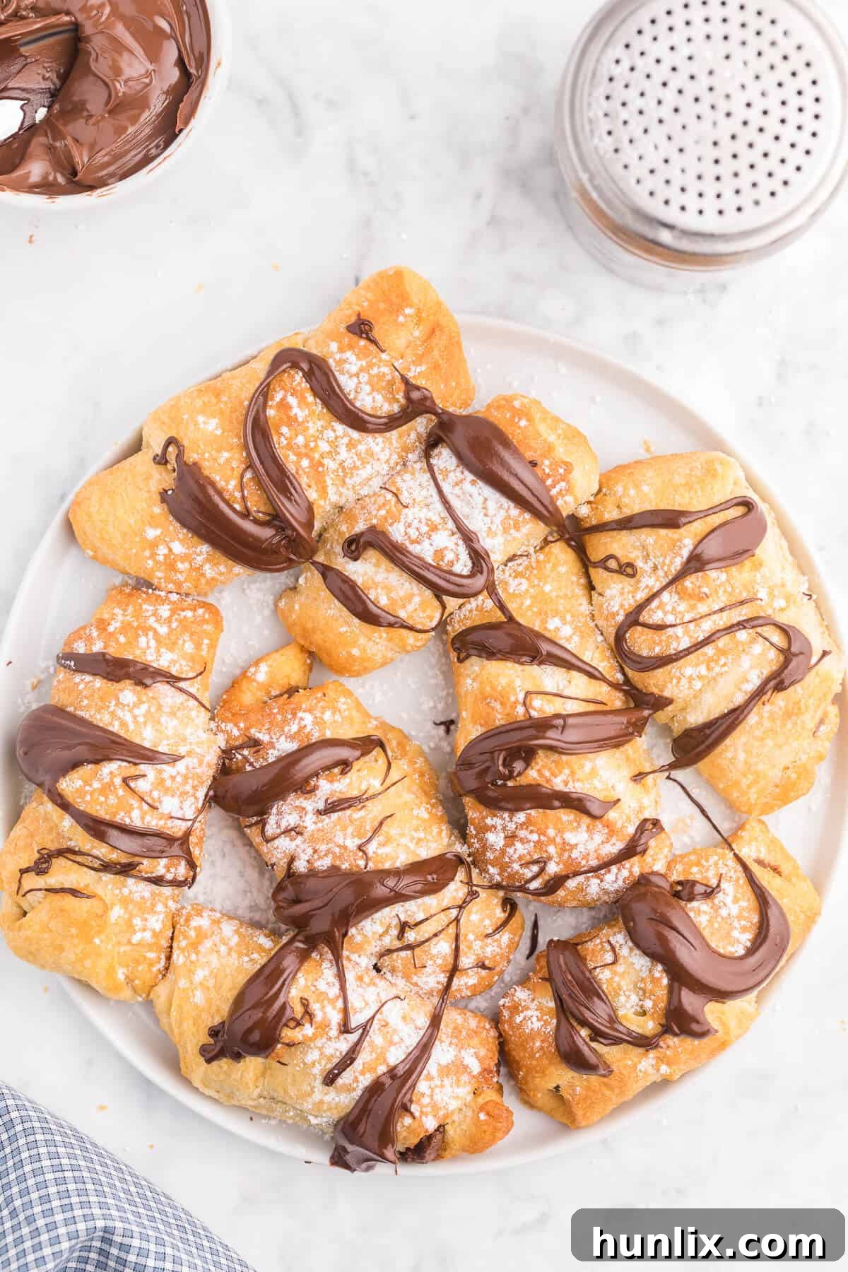 Perfect Air Fryer Chocolate Croissants 2 Golden brown Air Fryer Chocolate Crescent Rolls on a white plate, ready to be enjoyed.