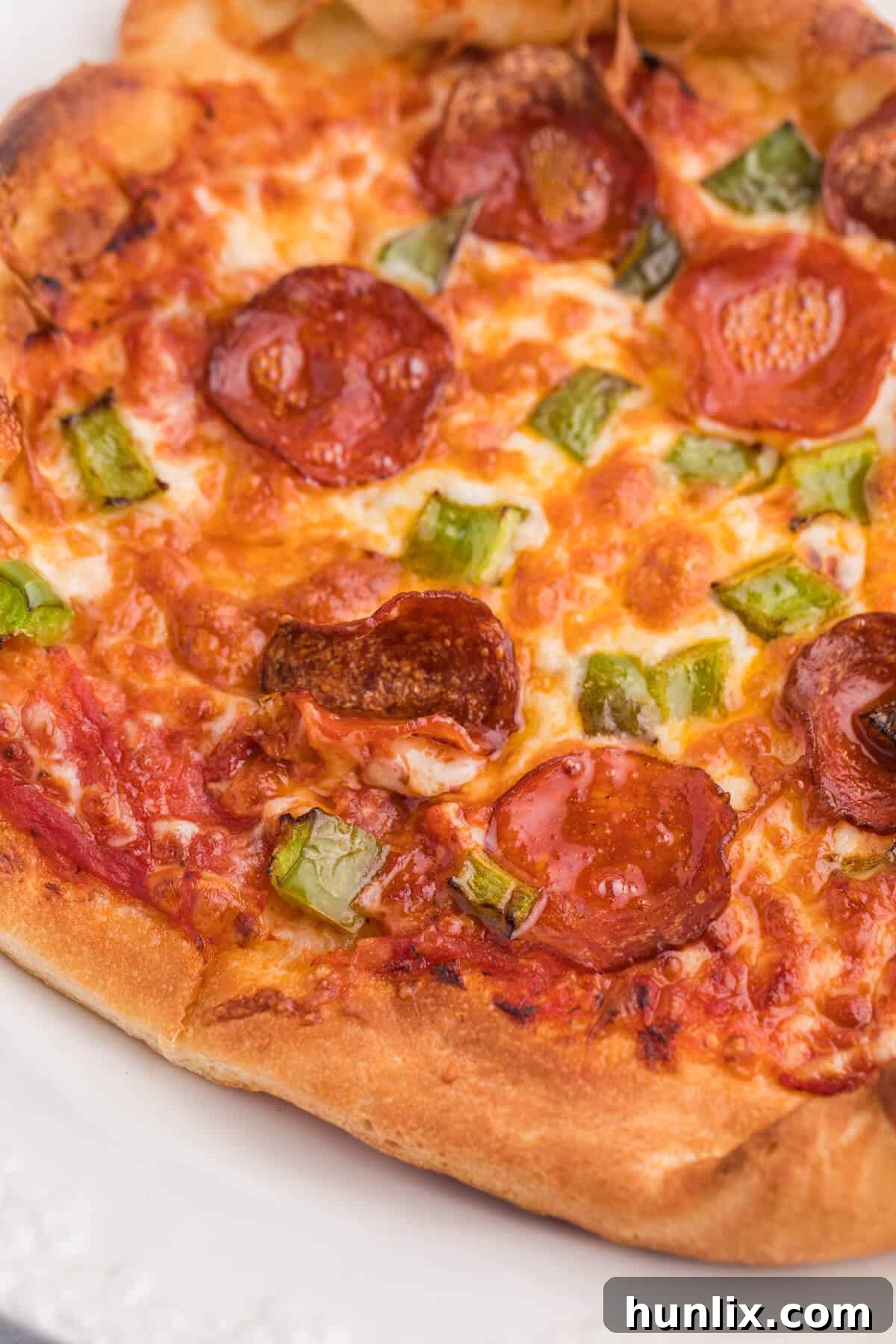 A close-up view of a delicious air fryer pizza, showcasing the melted mozzarella cheese, pepperoni, and green peppers on a perfectly baked crust.