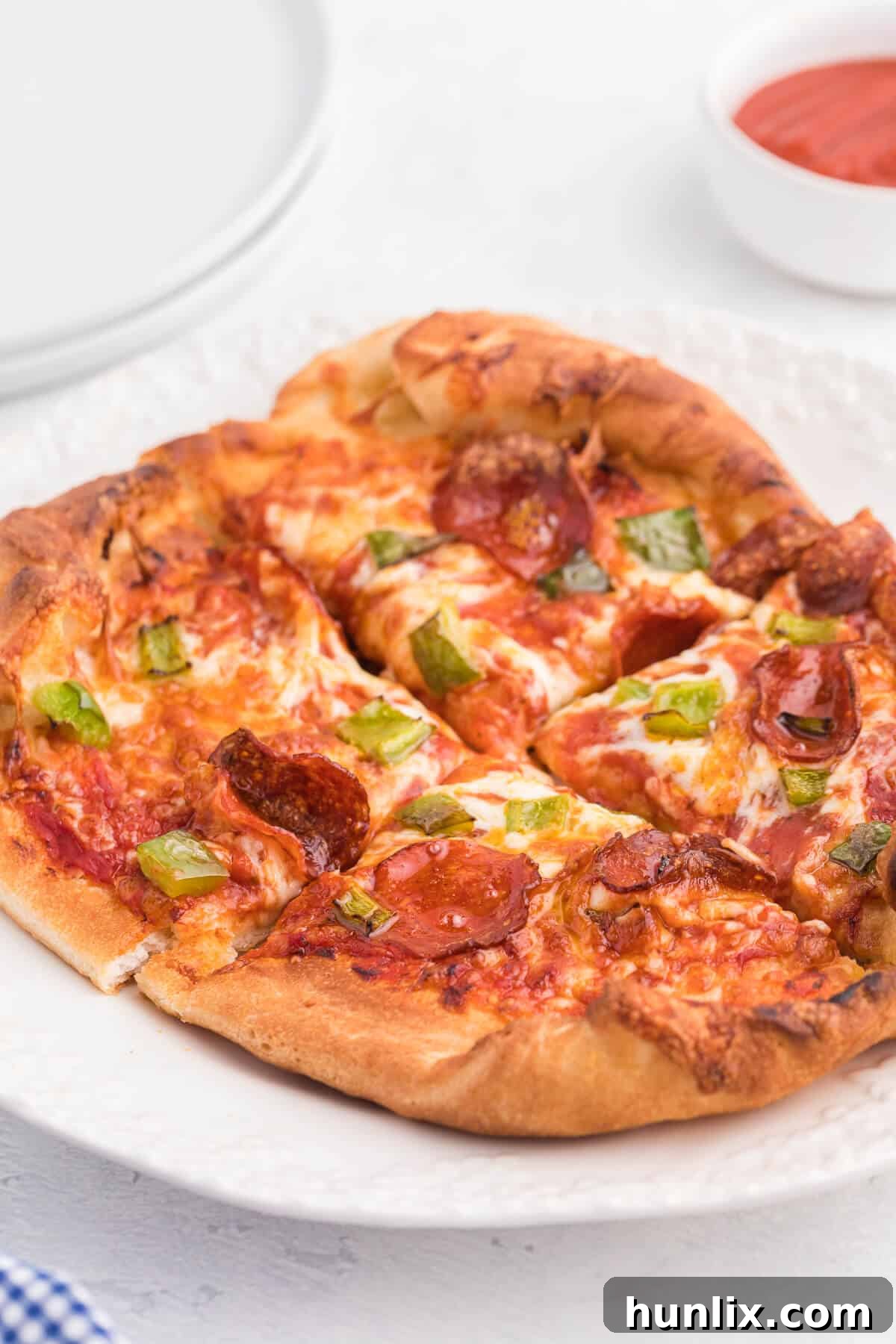 Slices of air fryer pizza on a white plate, highlighting the crispy crust and perfectly melted cheese.