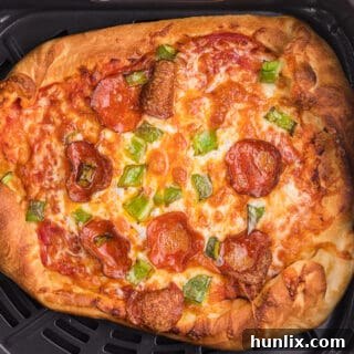 An air fryer pizza cooking in the basket, showing bubbling cheese and a crispy crust.