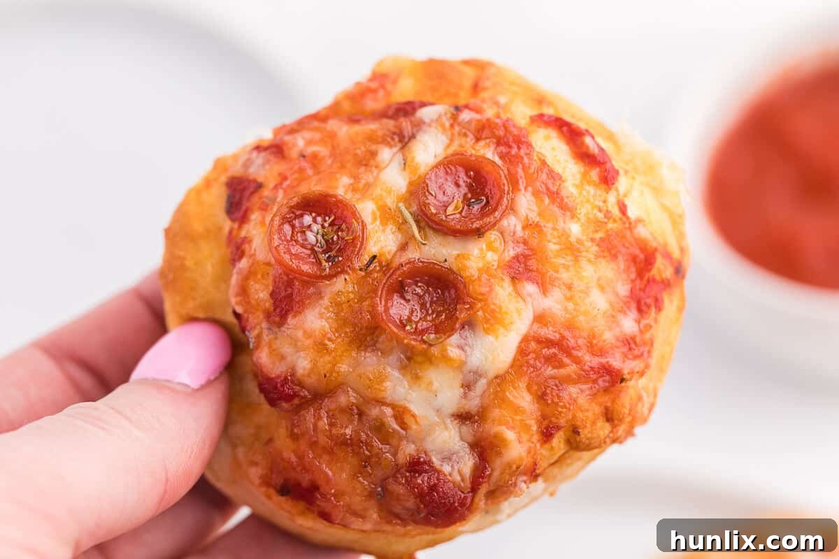Irresistible Air Fryer Pizza Buns 8 A hand reaching for one of the freshly made air fryer pizza buns.