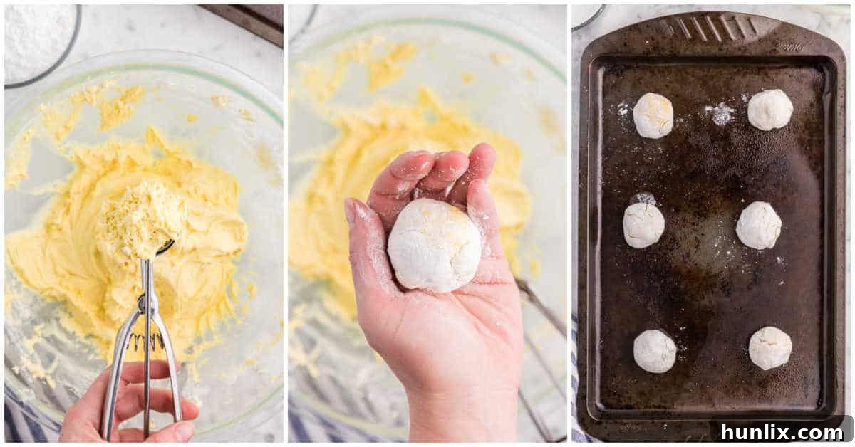 Cool Whip cookie dough balls coated in powdered sugar, ready for baking on a greased cookie sheet.