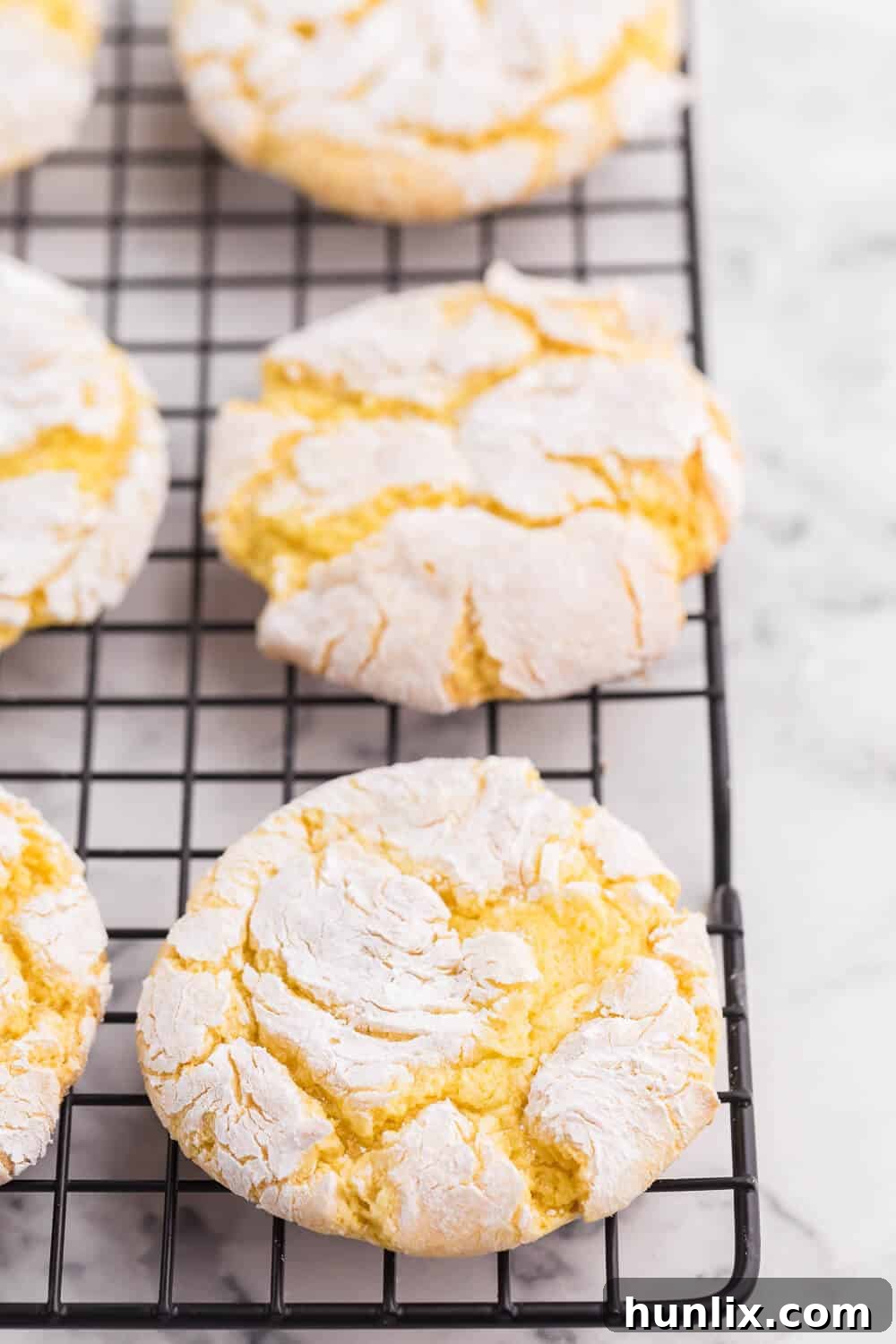 A batch of freshly baked Cool Whip Cookies, perfectly round and crinkly, cooling on a wire rack.