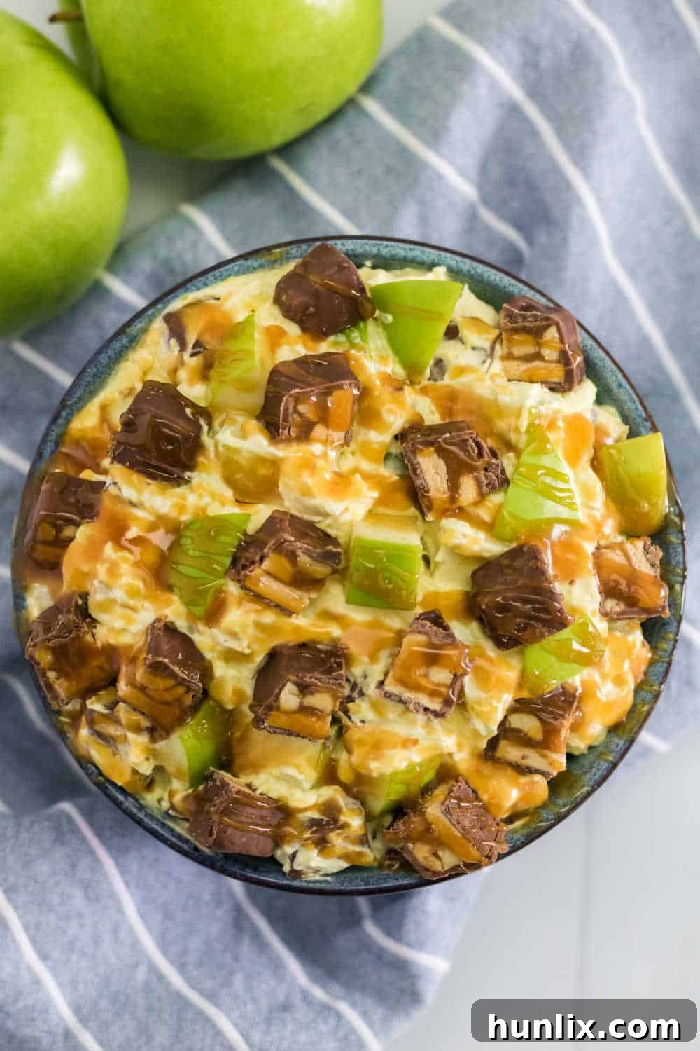 Creamy Caramel Snickers Apple Salad 2 A beautifully presented bowl of vibrant Snickers Salad, showcasing chunks of Snickers, crisp green apple pieces, and creamy dressing, garnished with a caramel drizzle.