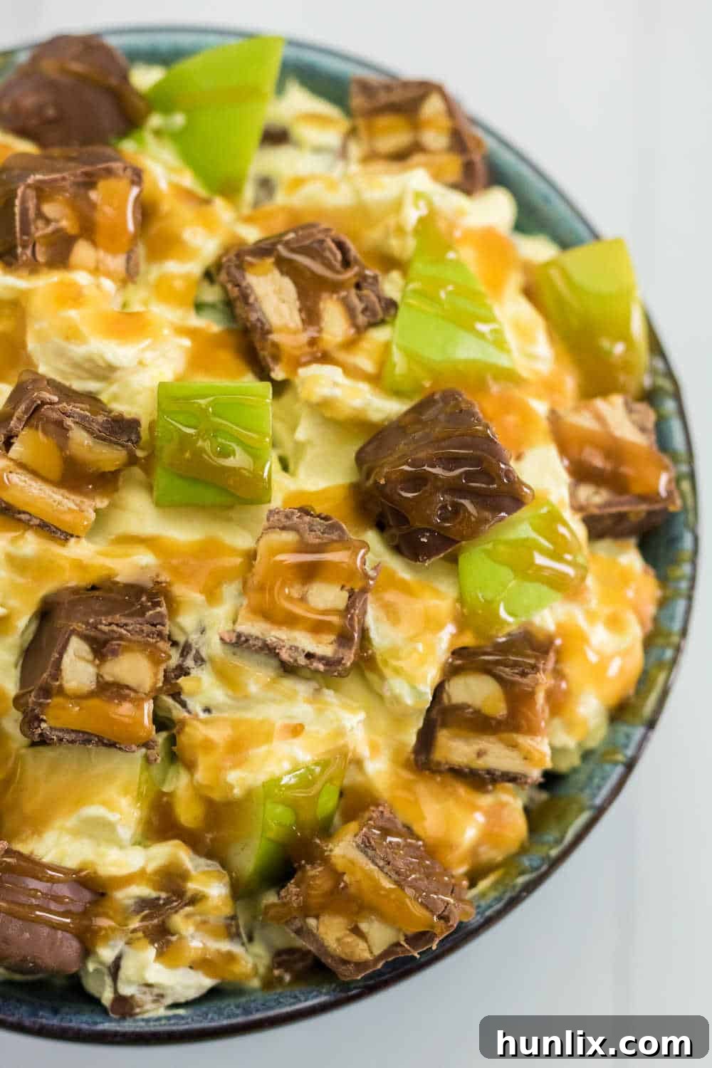 Creamy Caramel Snickers Apple Salad 6 A freshly prepared bowl of Snickers Salad, generously topped with luscious caramel sauce and ready to be served.