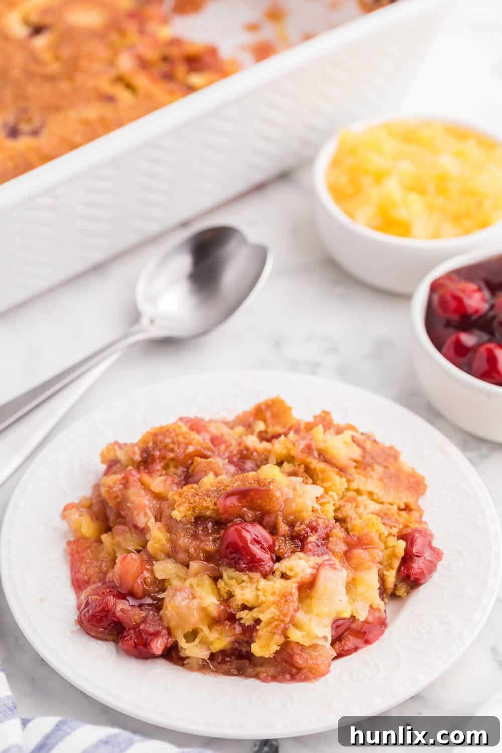 A single slice of Cherry Pineapple Dump Cake on a white plate, showcasing the distinct layers.