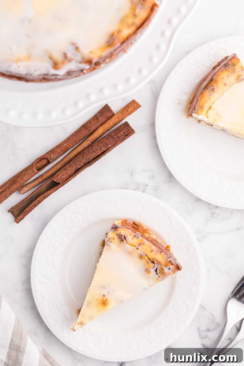 A pristine slice of Cinnamon Roll Cheesecake presented on a simple white plate, highlighting its luscious layers.