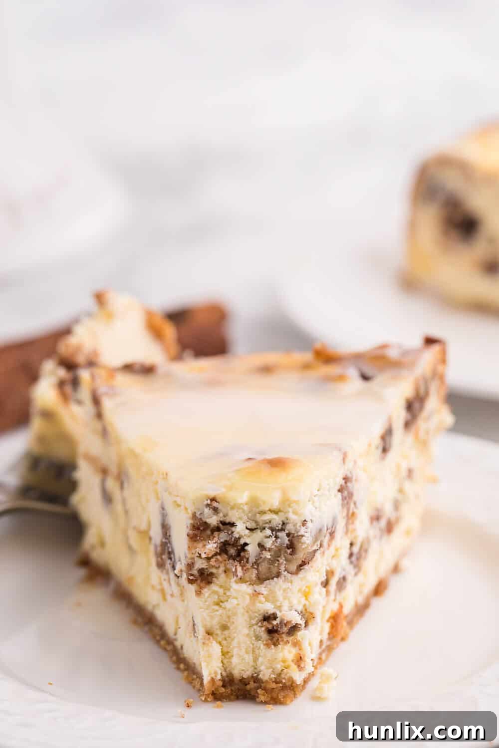 A tempting slice of cinnamon roll cheesecake with a perfect bite taken, showcasing its exquisite layers and texture.