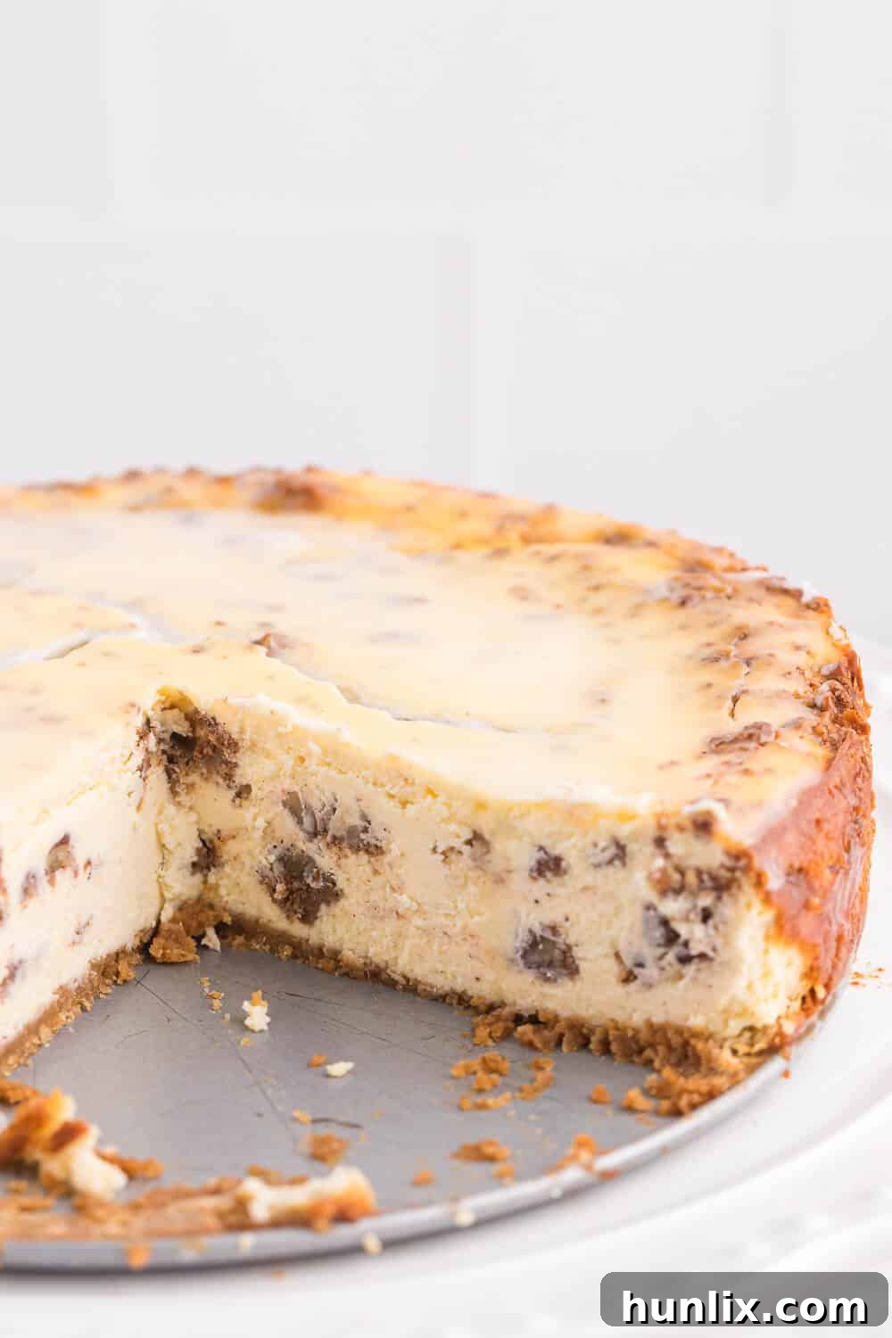 A stunning whole cinnamon roll cheesecake with a few slices already removed, showcasing its delicious interior.