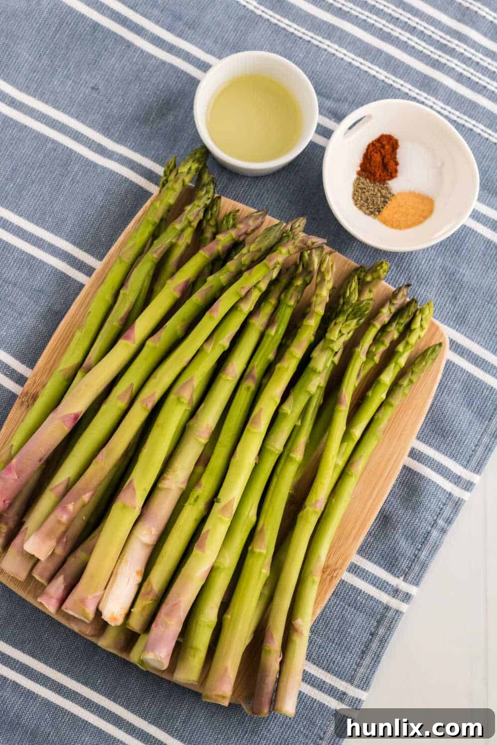 Ingredients for air fryer asparagus laid out on a blue and white striped linen.