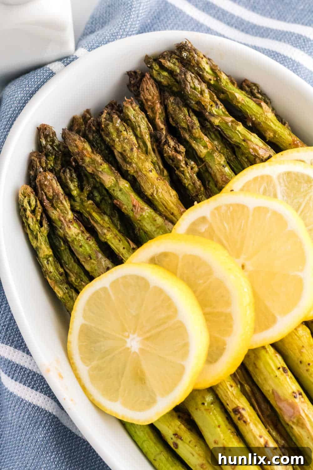 The air fryer asparagus recipe topped with lemon slices.