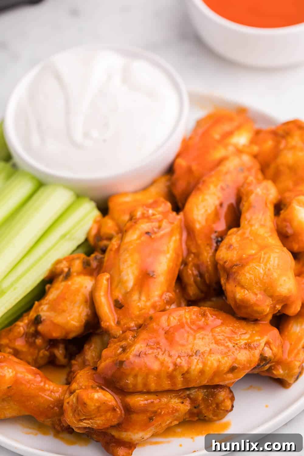 A beautifully arranged plate of Air Fryer Buffalo Chicken Wings, garnished with celery sticks and served with a side of creamy dip.