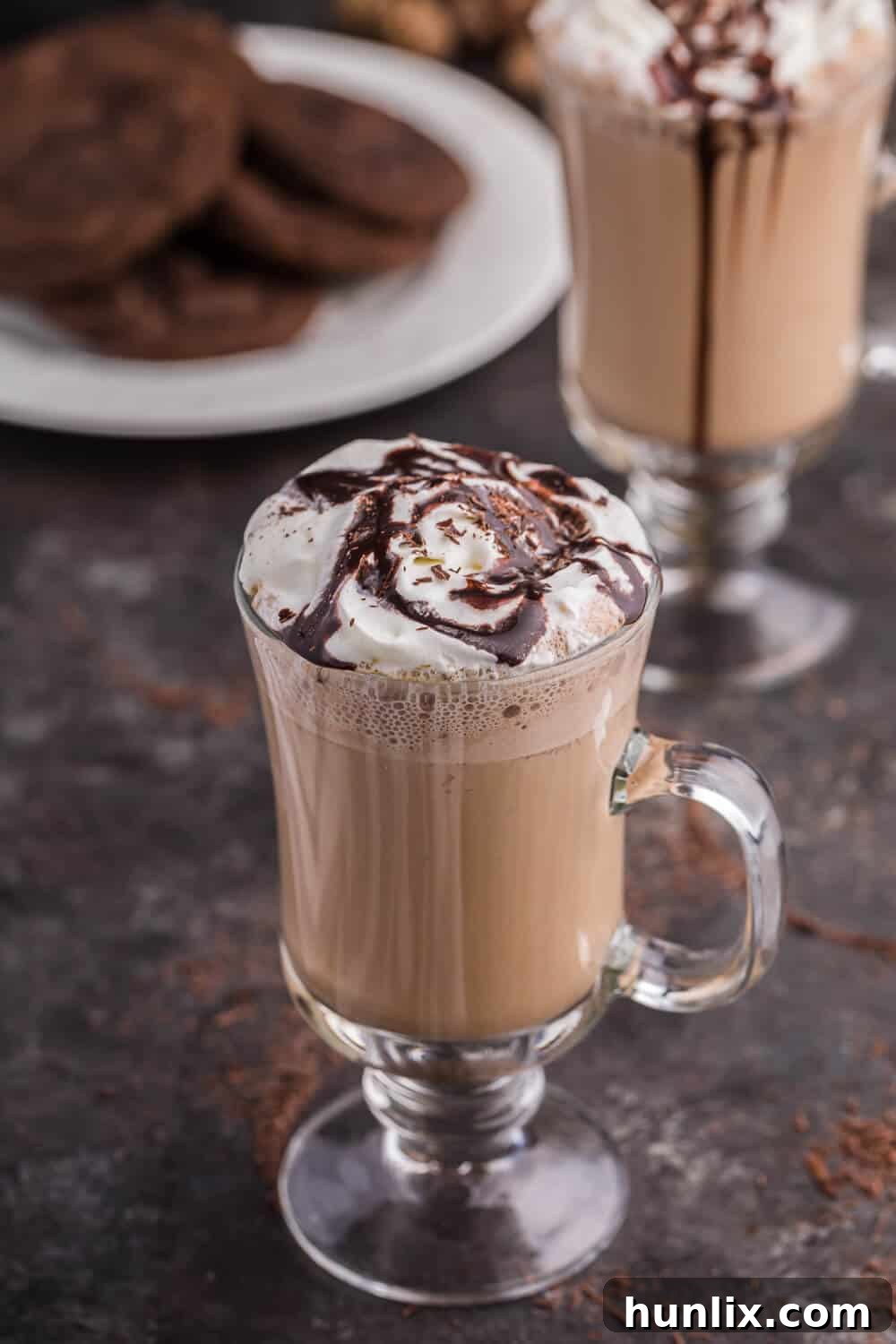 A beautifully presented glass mug of mocha latte, topped with whipped cream and chocolate shavings.