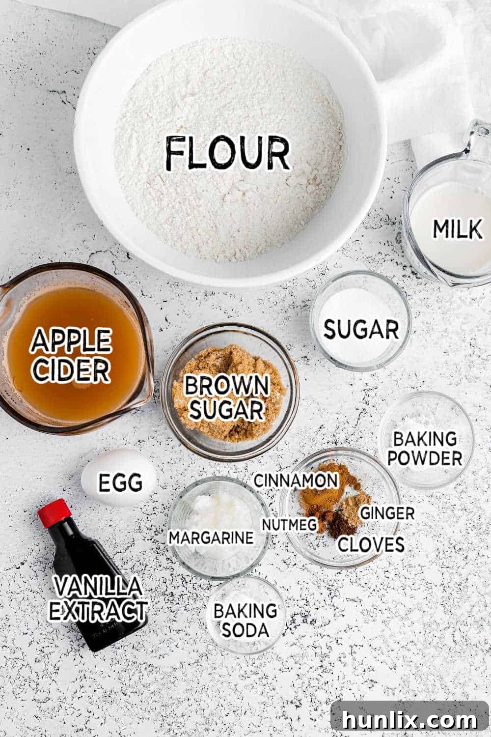 A vibrant flat lay image showcasing all the fresh, high-quality ingredients laid out neatly for making baked apple cider donuts, including apples, spices, flour, and liquid ingredients.