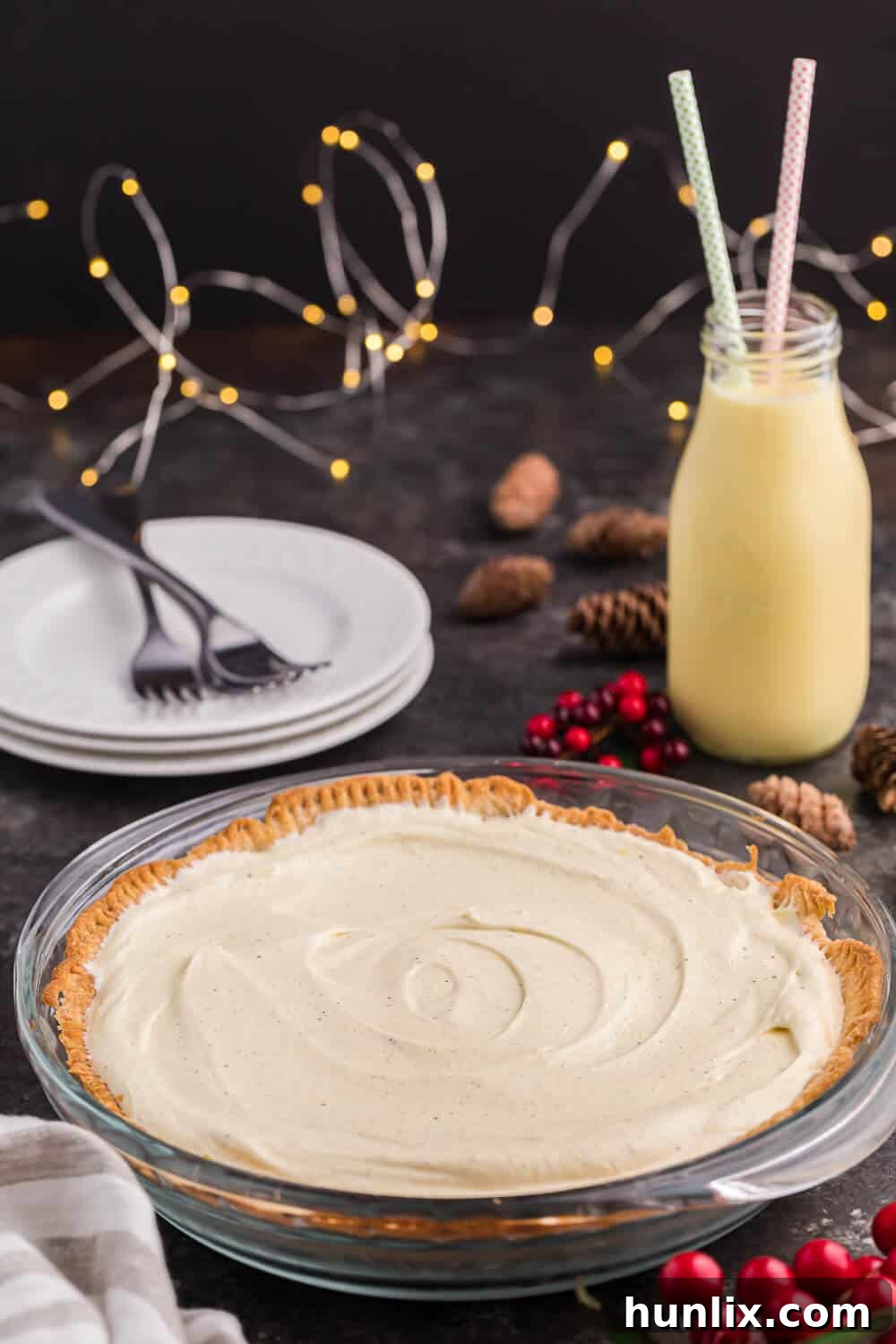 Eggnog pie with a glass of eggnog and holiday decor, showcasing a perfect slice.