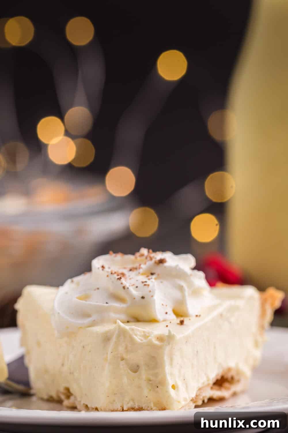 A slice of eggnog pie on a plate with a bite taken off the end, showing its creamy texture.