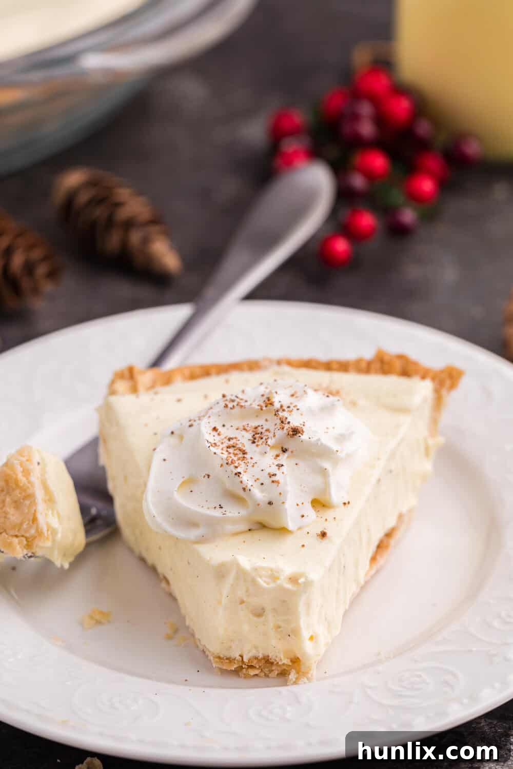 A slice of eggnog pie on a plate with a fork, ready to be enjoyed.