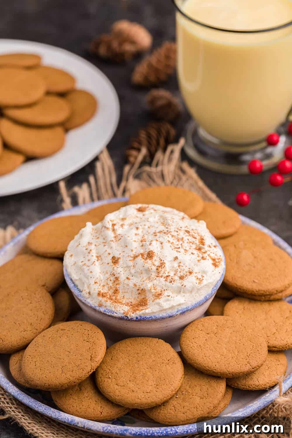 A festive serving bowl of Eggnog Dip surrounded by a variety of gingersnap cookies, ready for a holiday party.